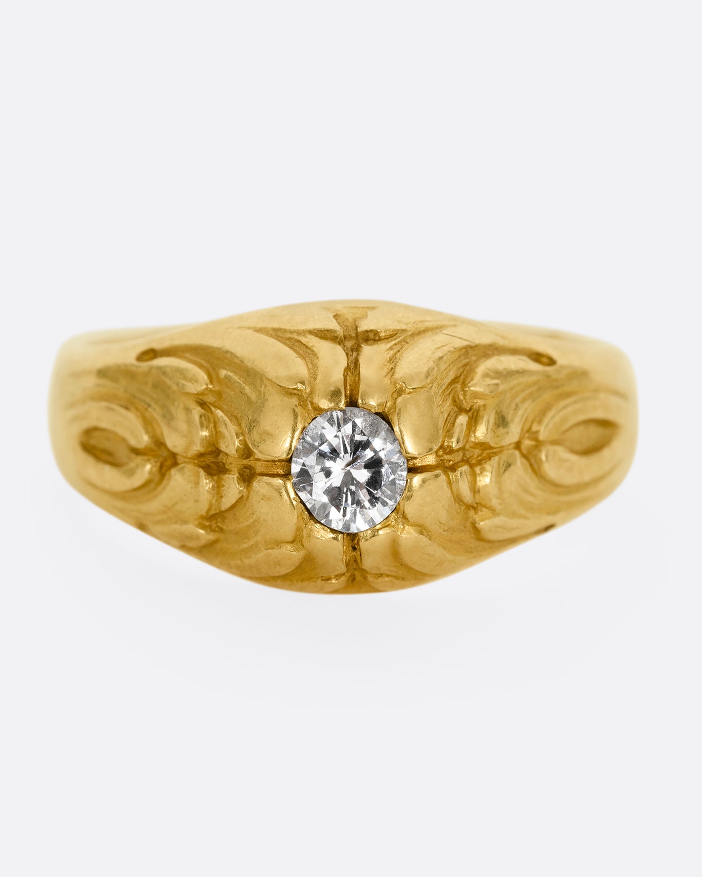 A yellow gold dome ring with  textural waves on its top and a round central diamond. Shown from the front.
