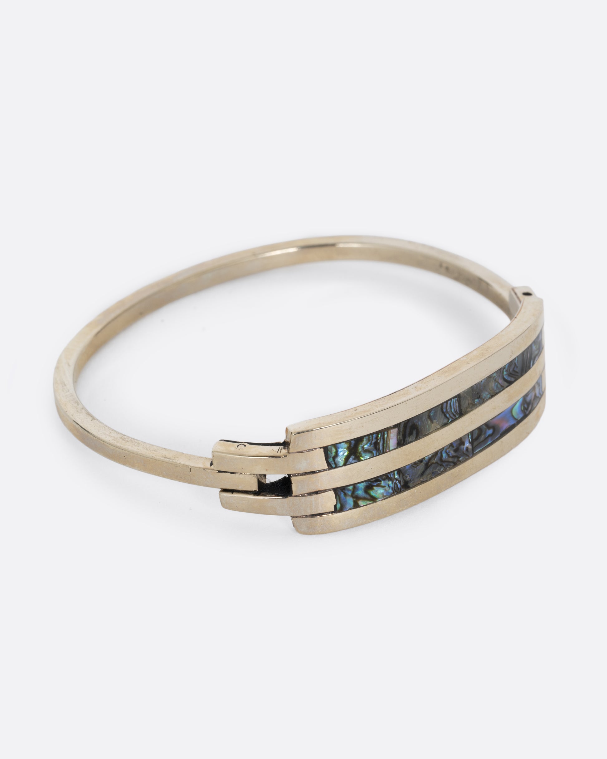 An alpaca silver bracelet with two abalone stripes and a hinged clasp. Shown from the side.