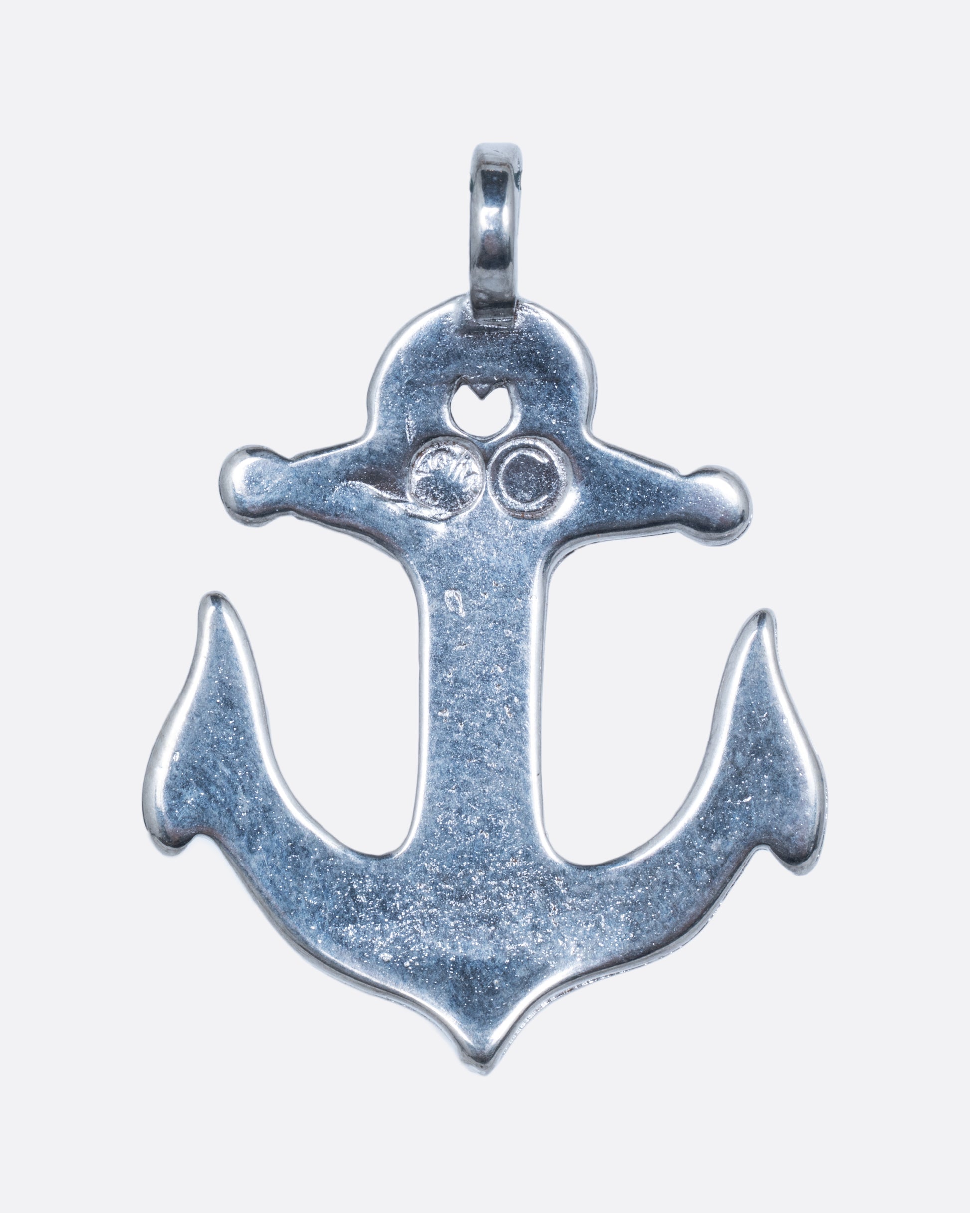 An alpaca silver anchor charm with turquoise chip inlay. Shown from the back.