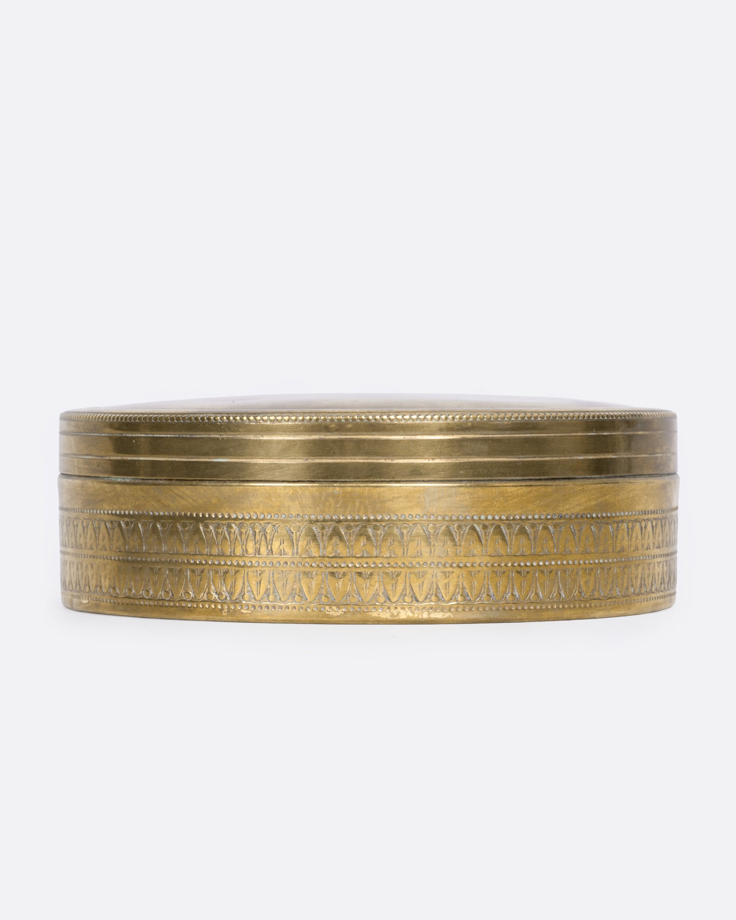 A circular brass box with a lid, shown from the side.