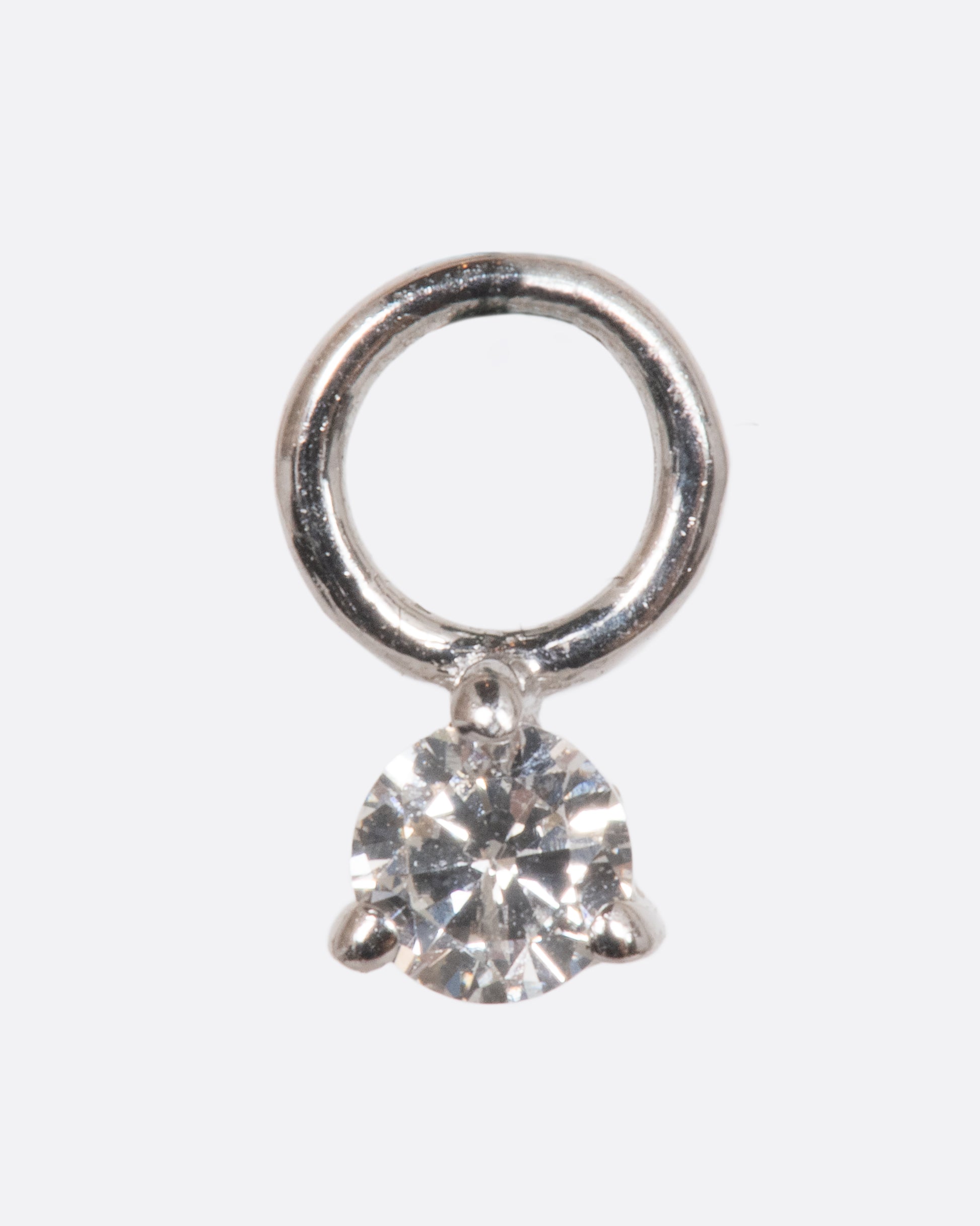 A dangle with a white gold prong setting and jump ring and a white diamond. Shown from the front.