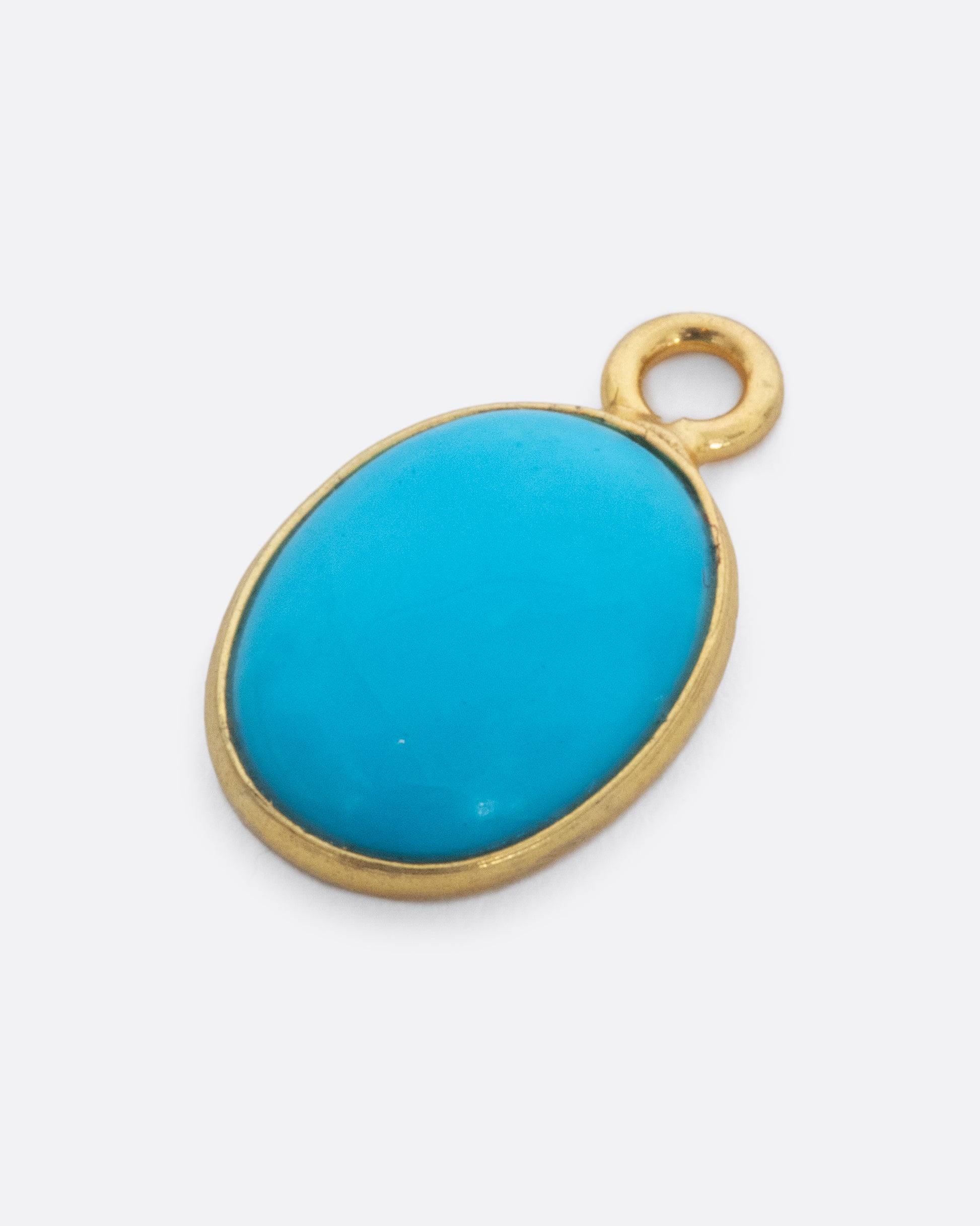  A Sleeping Beauty Turquoise dangle set in yellow gold with a yellow gold bail. Shown lying flat from the front.
