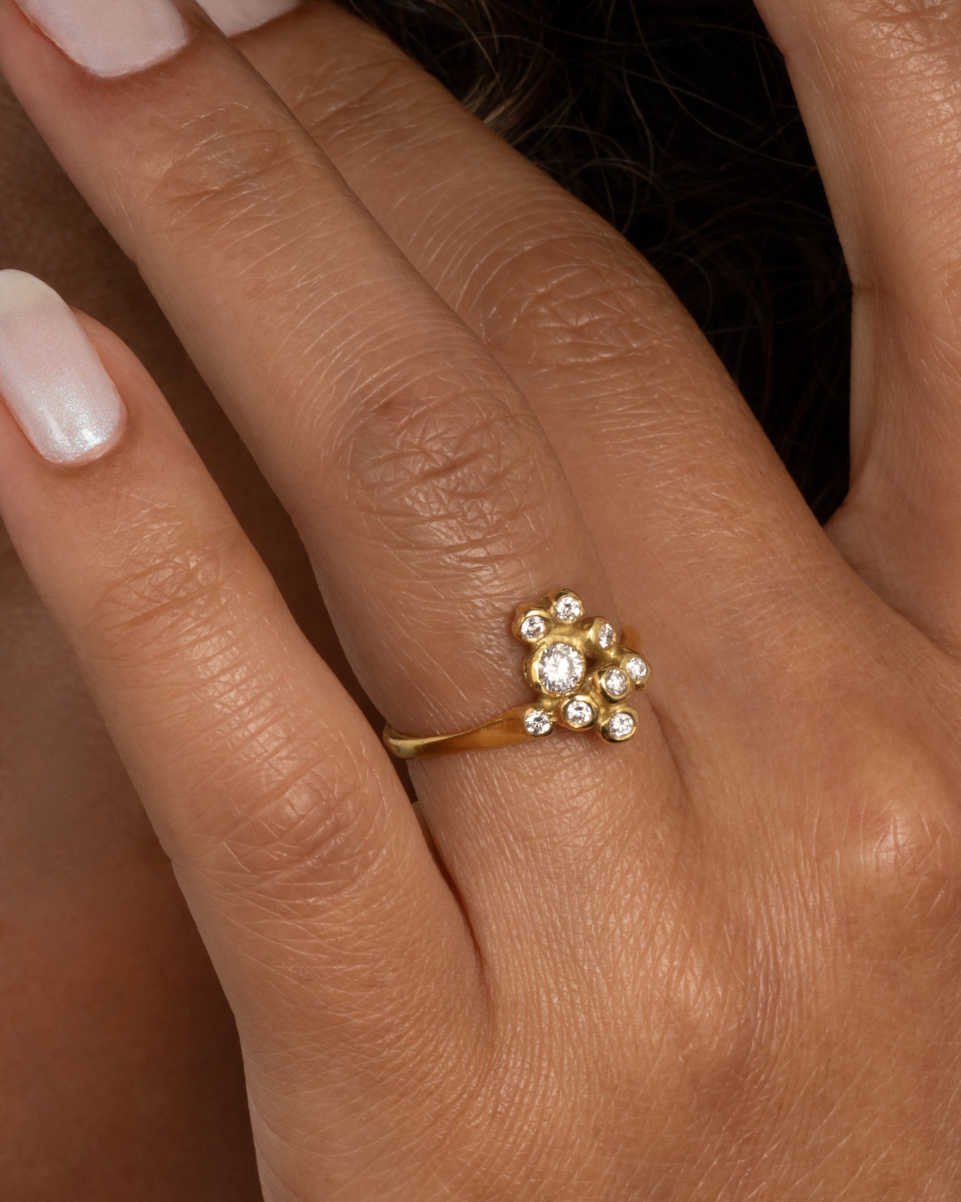 18k yellow gold blooming anemone ring with nine round diamonds by Kimberlin Brown, shown worn on a finger.