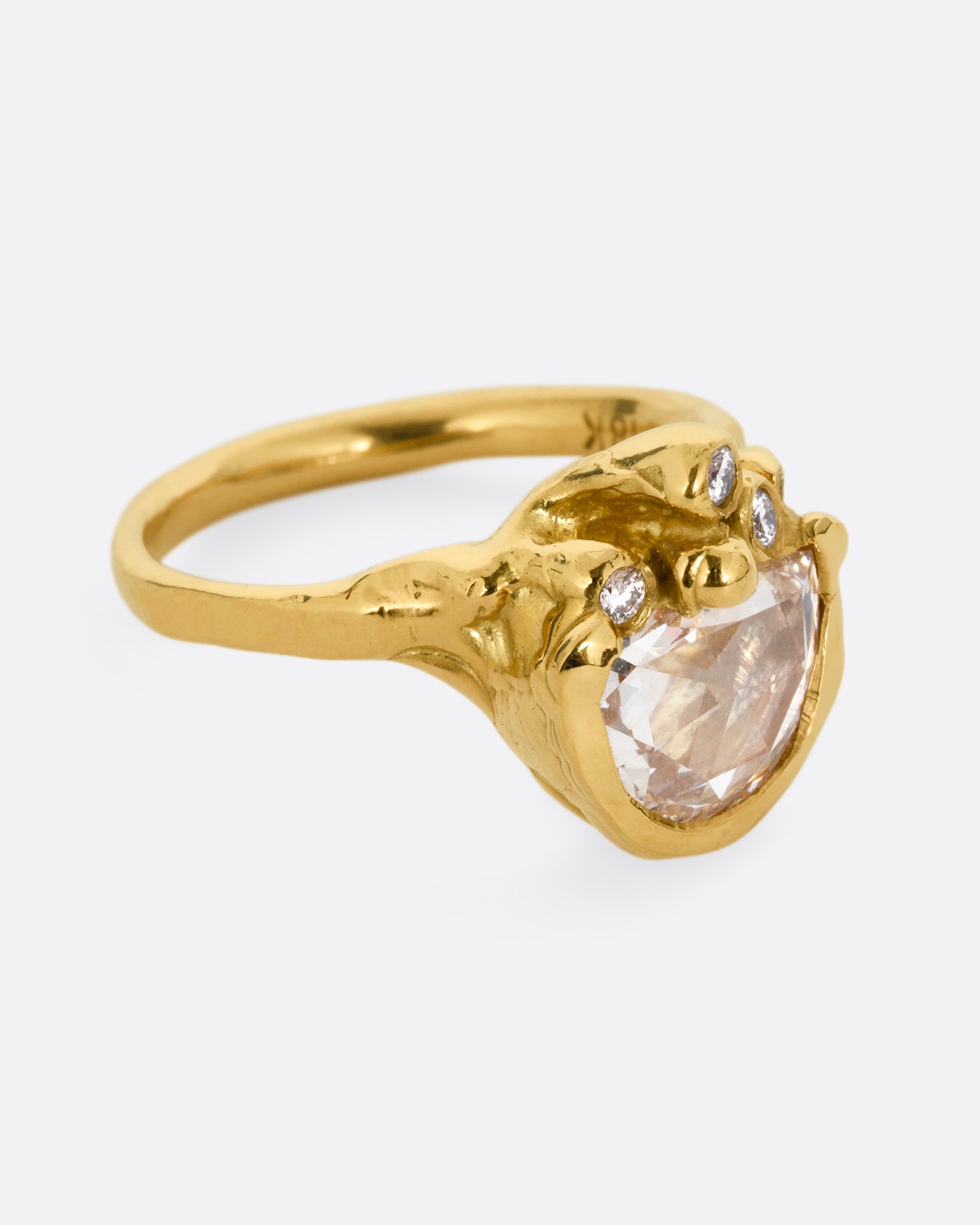 A yellow gold ring with  a central rose cut diamond half moon and bezel set diamond accents on top of the flat side. Shown from the side. 