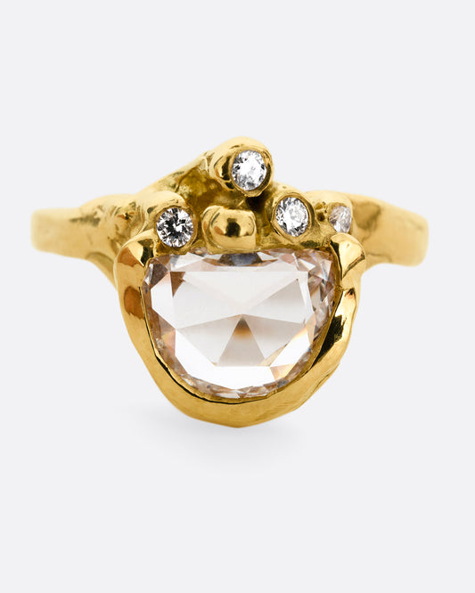 A yellow gold ring with  a central rose cut diamond half moon and bezel set diamond accents on top of the flat side. Shown from the front. 