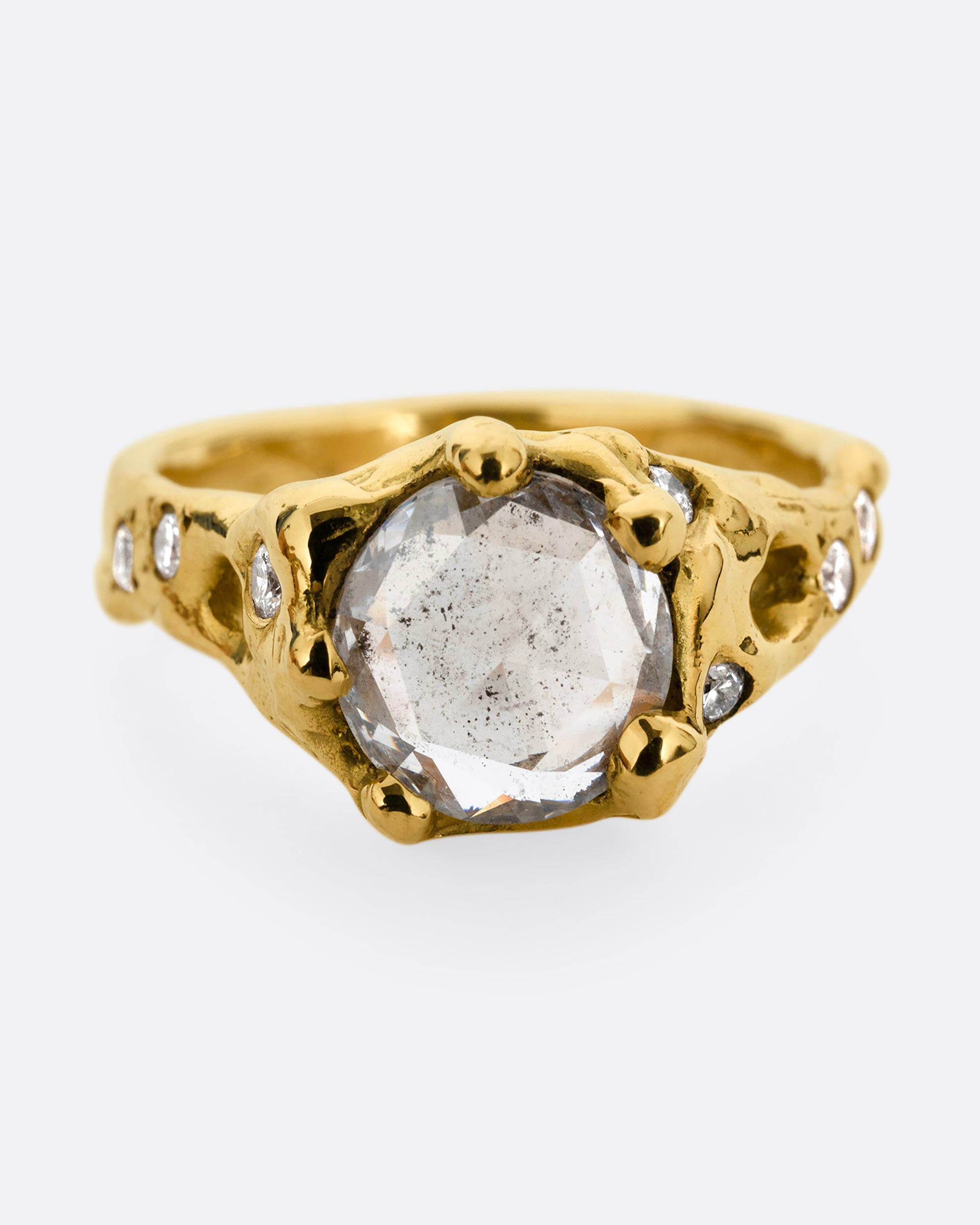 A yellow gold ring with a rose cut diamond, cutouts, and diamond details. Shown from the front.