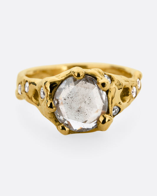 A yellow gold ring with a rose cut diamond, cutouts, and diamond details. Shown from the front.