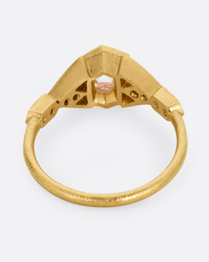 A yellow gold ring with a center diamond and angular side cutouts and diamond accents. Shown from the back.