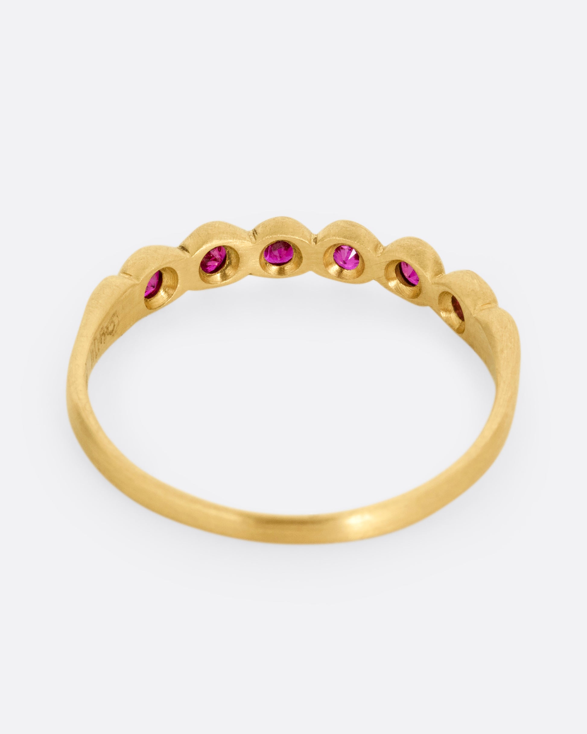 A yellow gold ring with six bezel set rubies. Shown from the back.