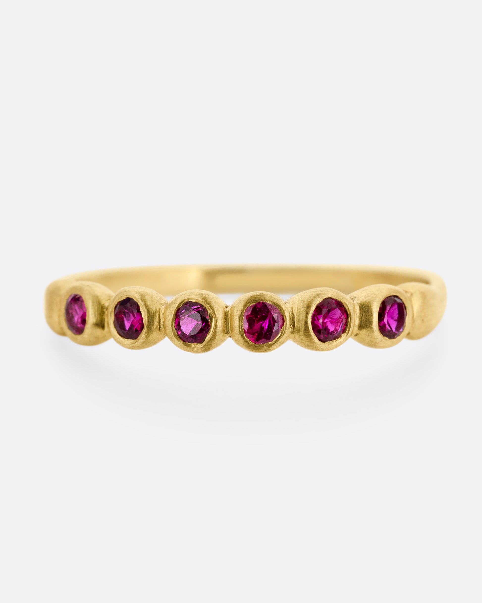 A yellow gold ring with six bezel set rubies. Shown from the front.