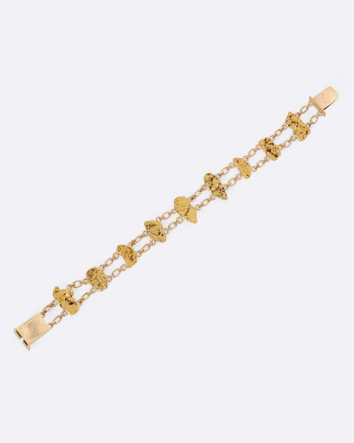 A yellow gold nugget bracelet featuring nine solid nuggets. View from above laying flat.