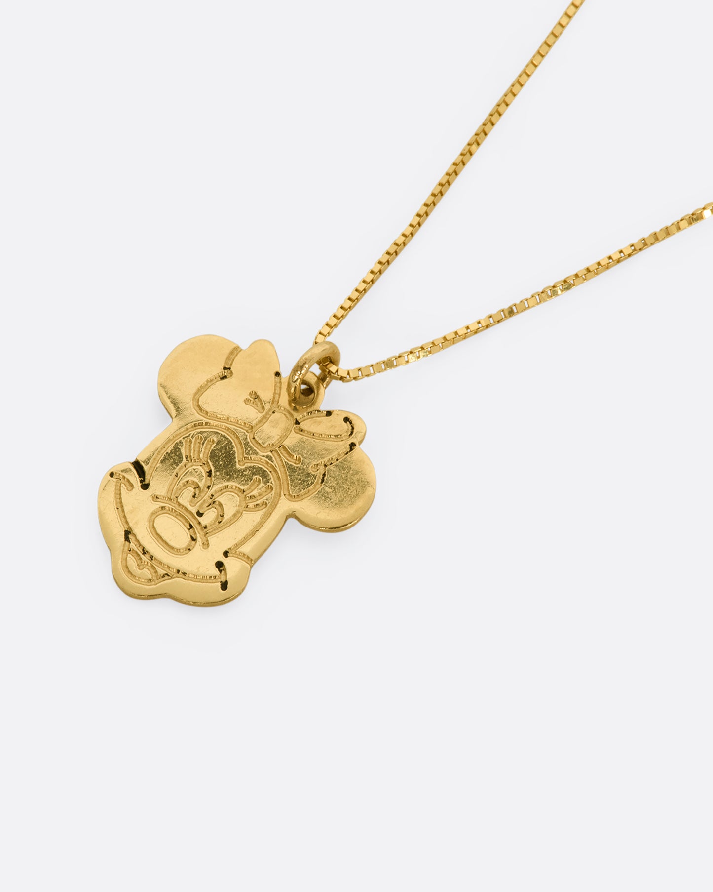 Yellow gold Minnie Mouse pendant hanging from box chain. View close up, laying flat.