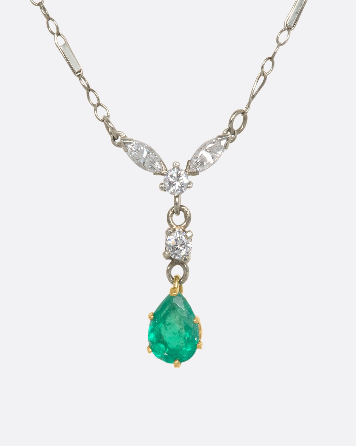 White gold necklace featuring diamonds and an emerald at the center. View close up from the front.