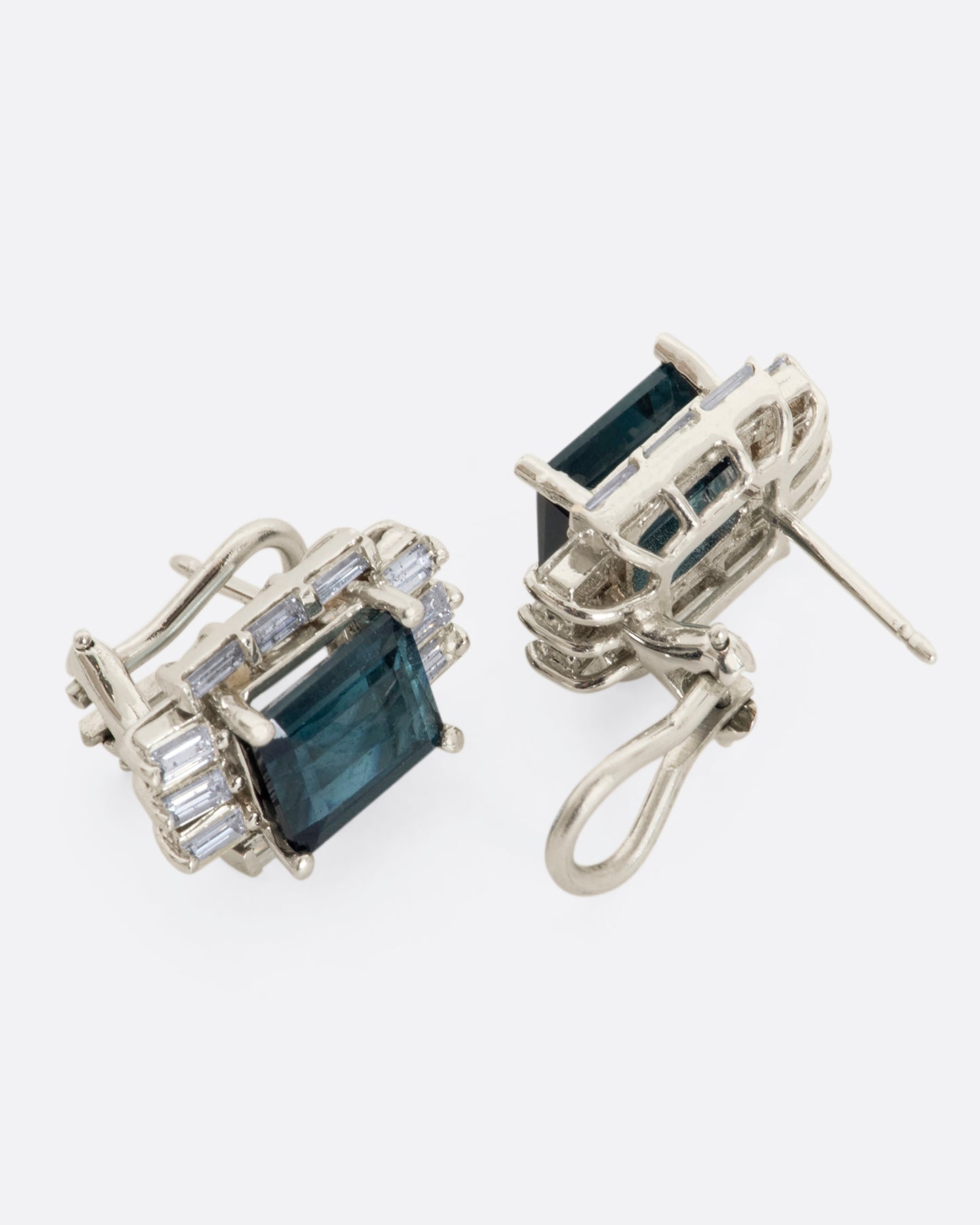 A pair of white gold earrings with emerald cut green tourmalines surrounded by baguette diamonds. View from the front and back alternating, showing clasp.