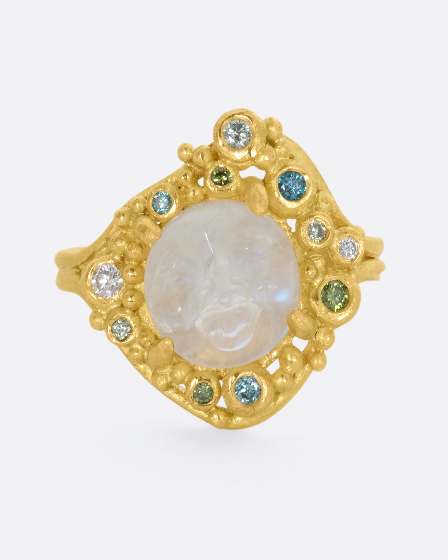 A yellow gold ring featuring a carved moonstone face with a halo of multicolored diamonds. View from the front. 