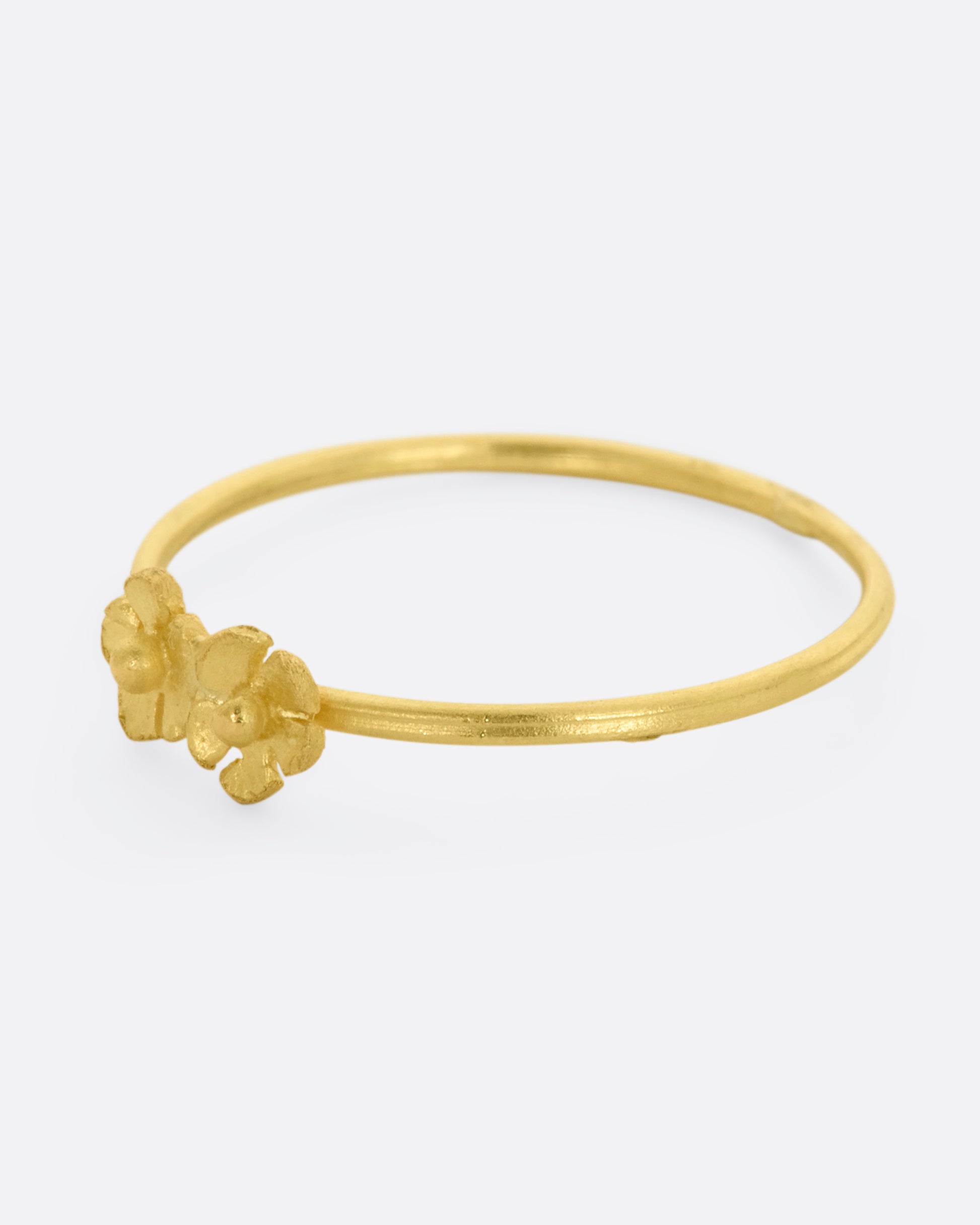 A ring with two yellow gold flowers on a dainty band. View from the left side.