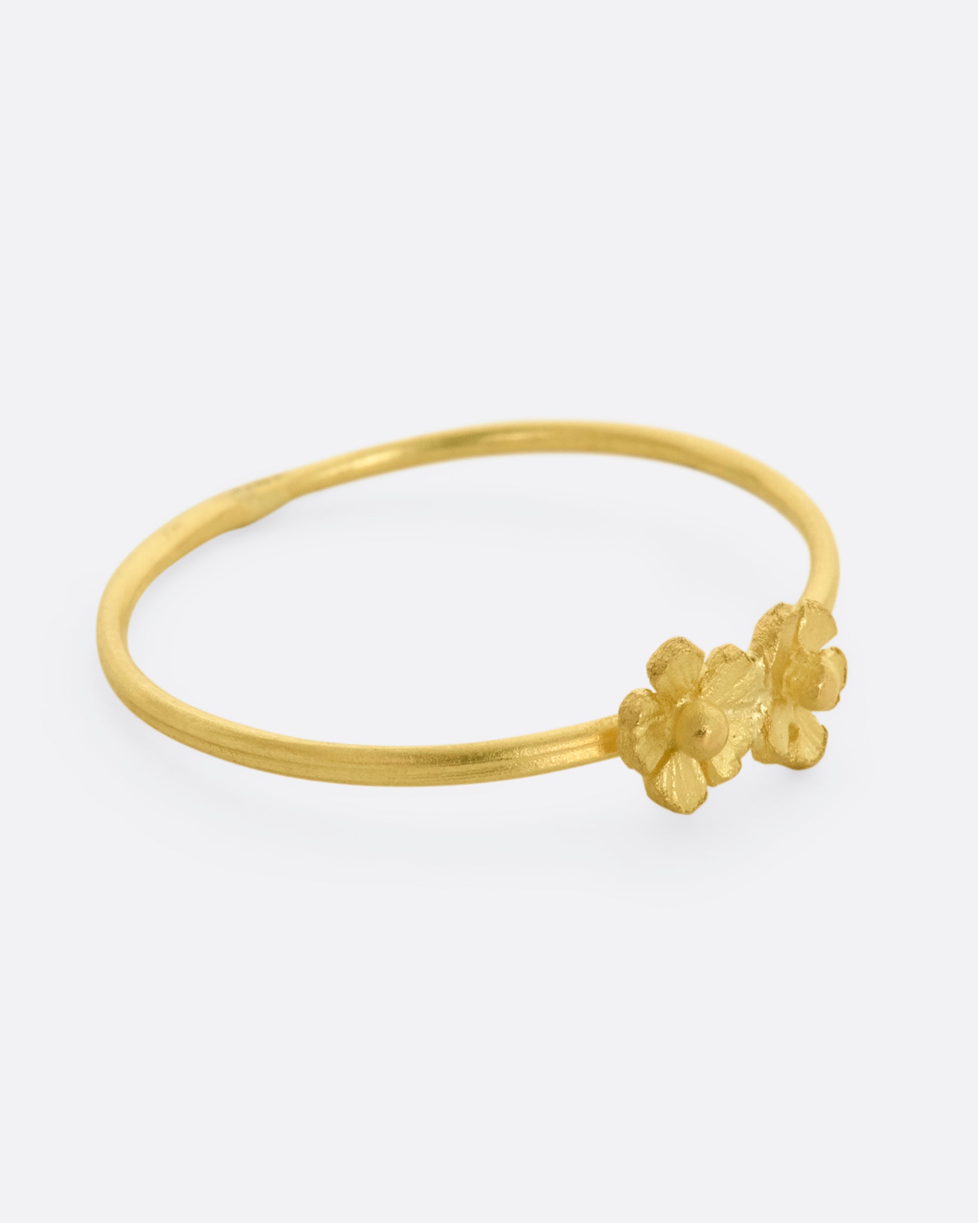 A ring with two yellow gold flowers on a dainty band. View from the right side.