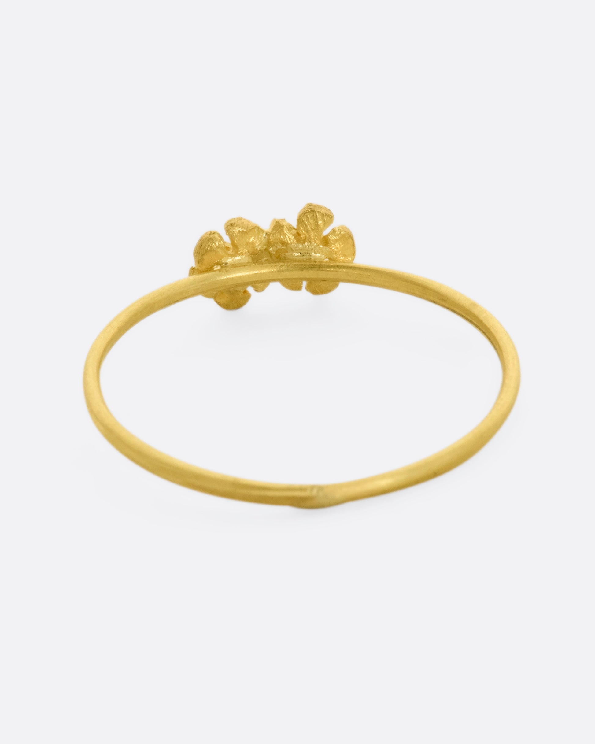 A ring with two yellow gold flowers on a dainty band. View from the back.