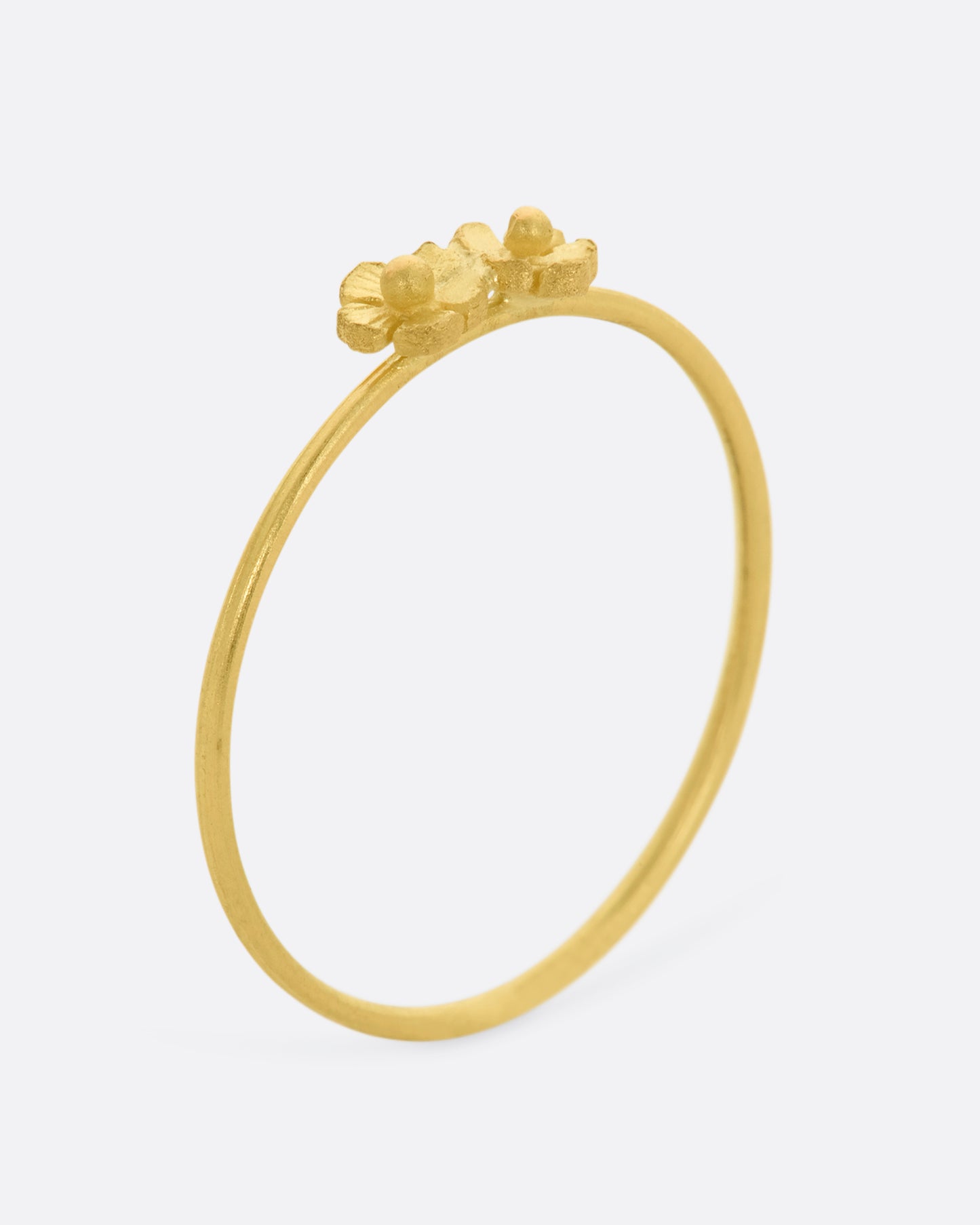 A ring with two yellow gold flowers on a dainty band. View from standing.