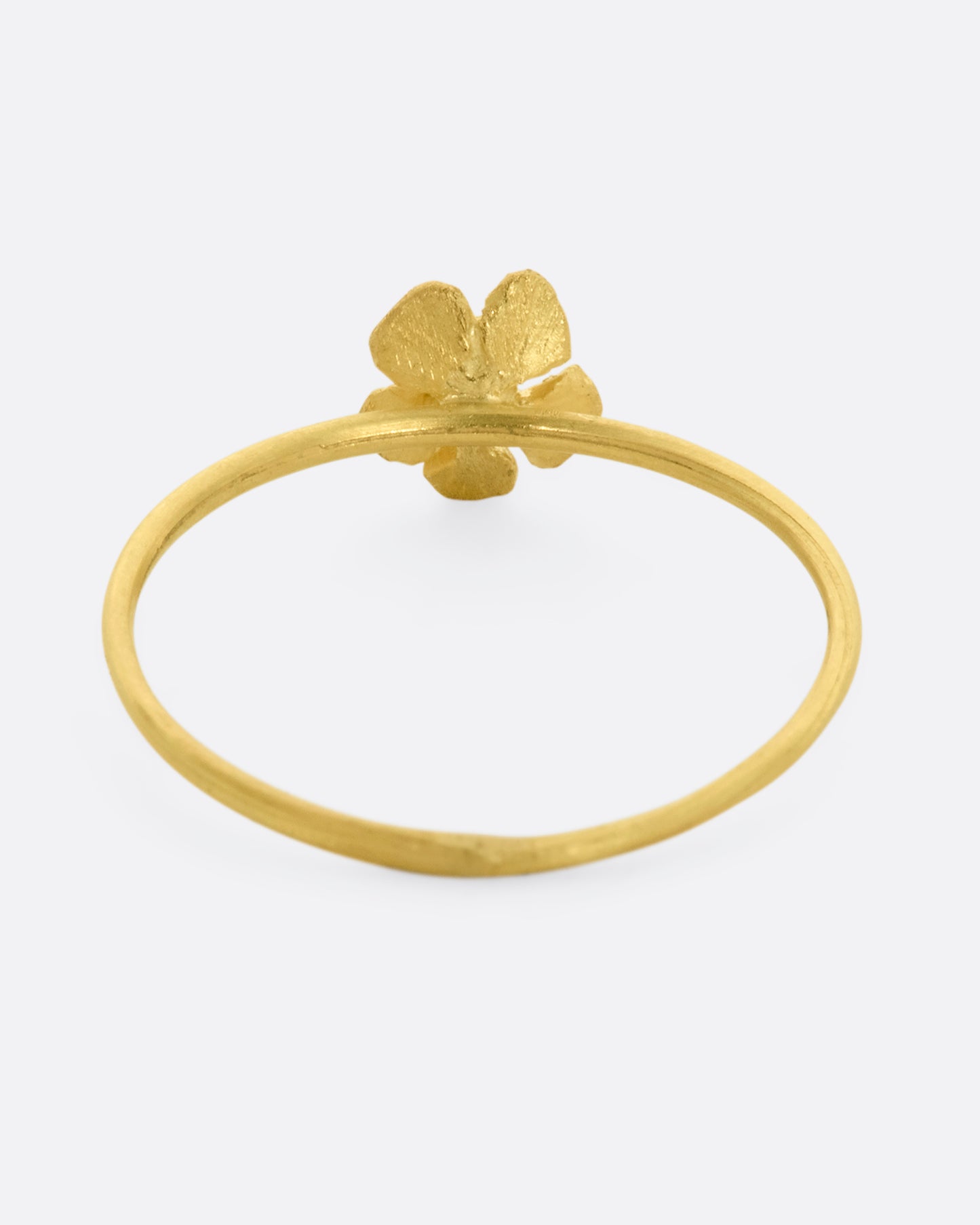 A small yellow gold flower with diamond at the center on a dainty band. View from the back.