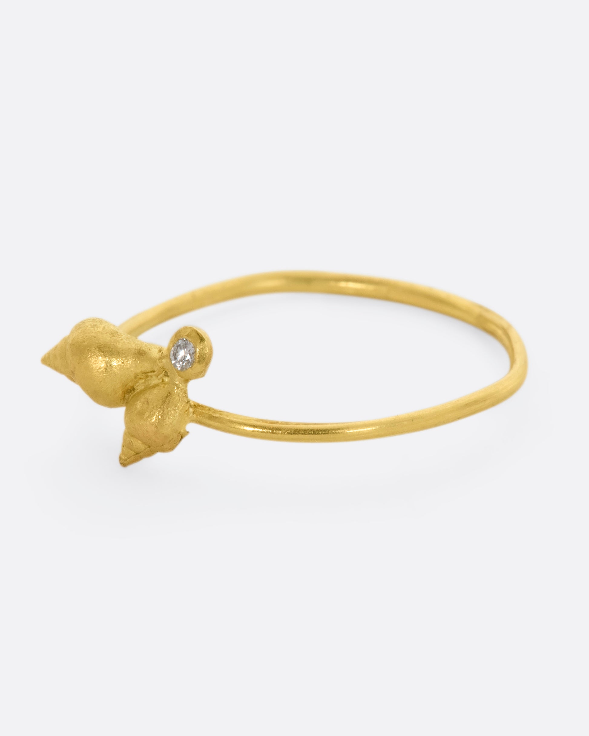 A ring with a cluster of two seashells and a diamond on a dainty band. View from the left side.