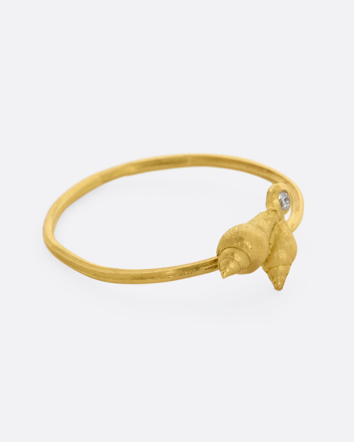 A ring with a cluster of two seashells and a diamond on a dainty band. View from the right side.