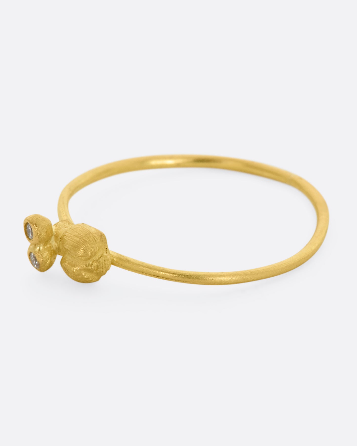 A yellow gold featuring a tiny bug with diamond eyes on a dainty band. View from the left side.