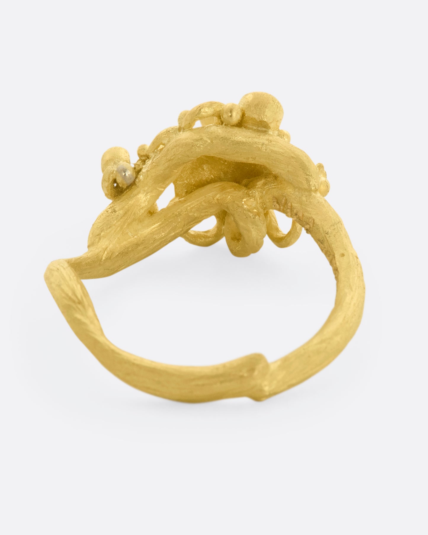 A yellow gold ring featuring an octopus with diamond eyes, surrounded by diamonds. View from the back.