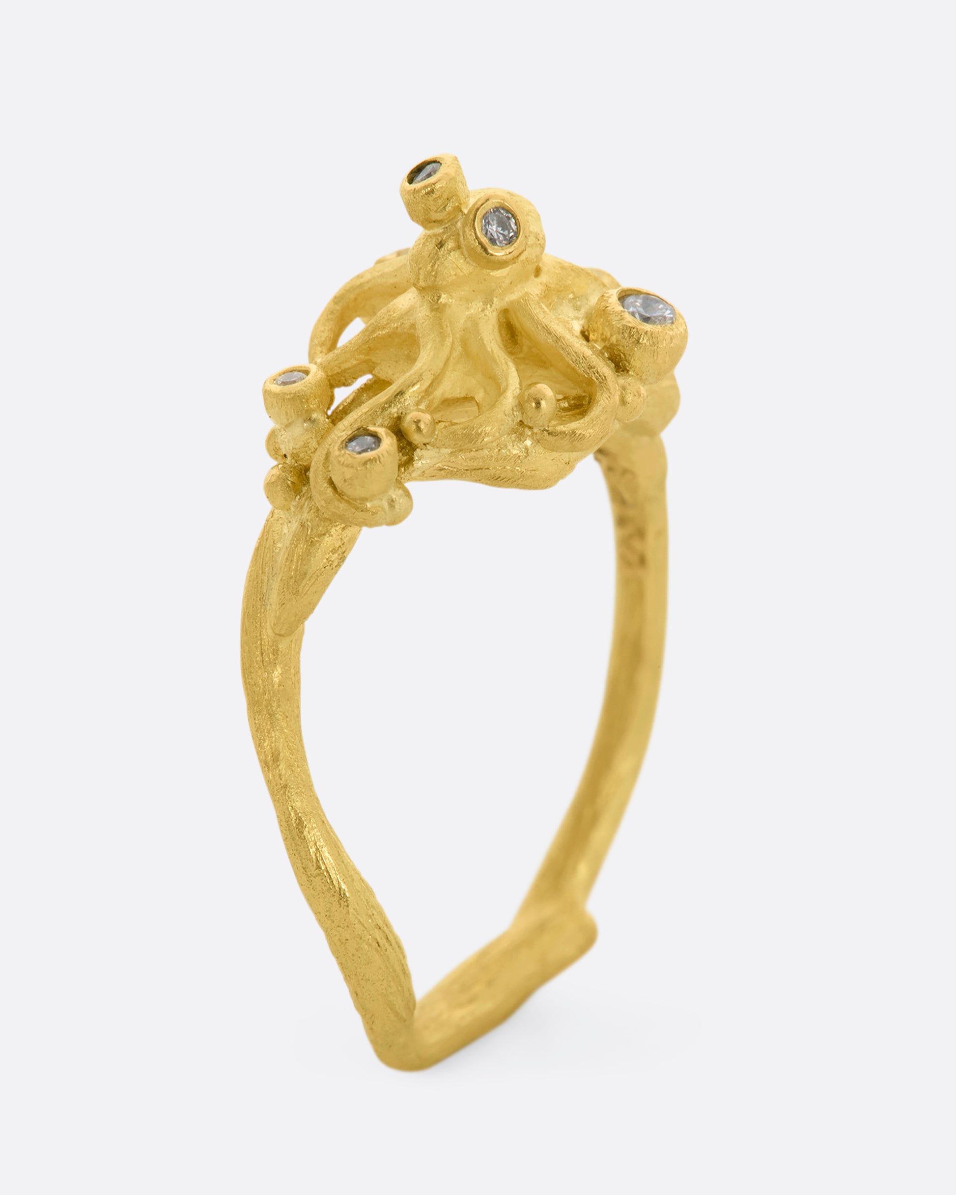 A yellow gold ring featuring an octopus with diamond eyes, surrounded by diamonds. View standing.