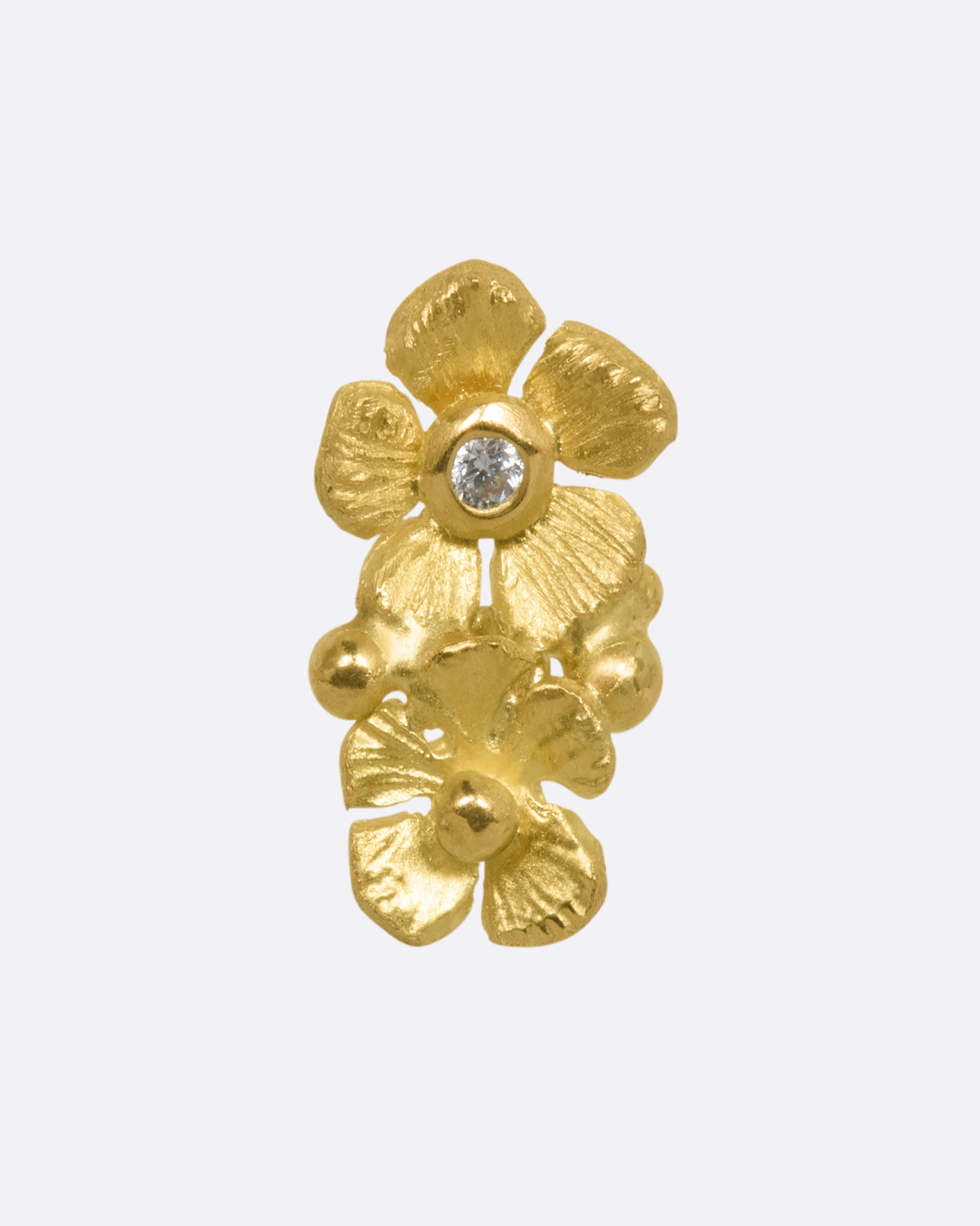 A yellow gold earring with two flowers, one with a diamond at the center. View from the front. 