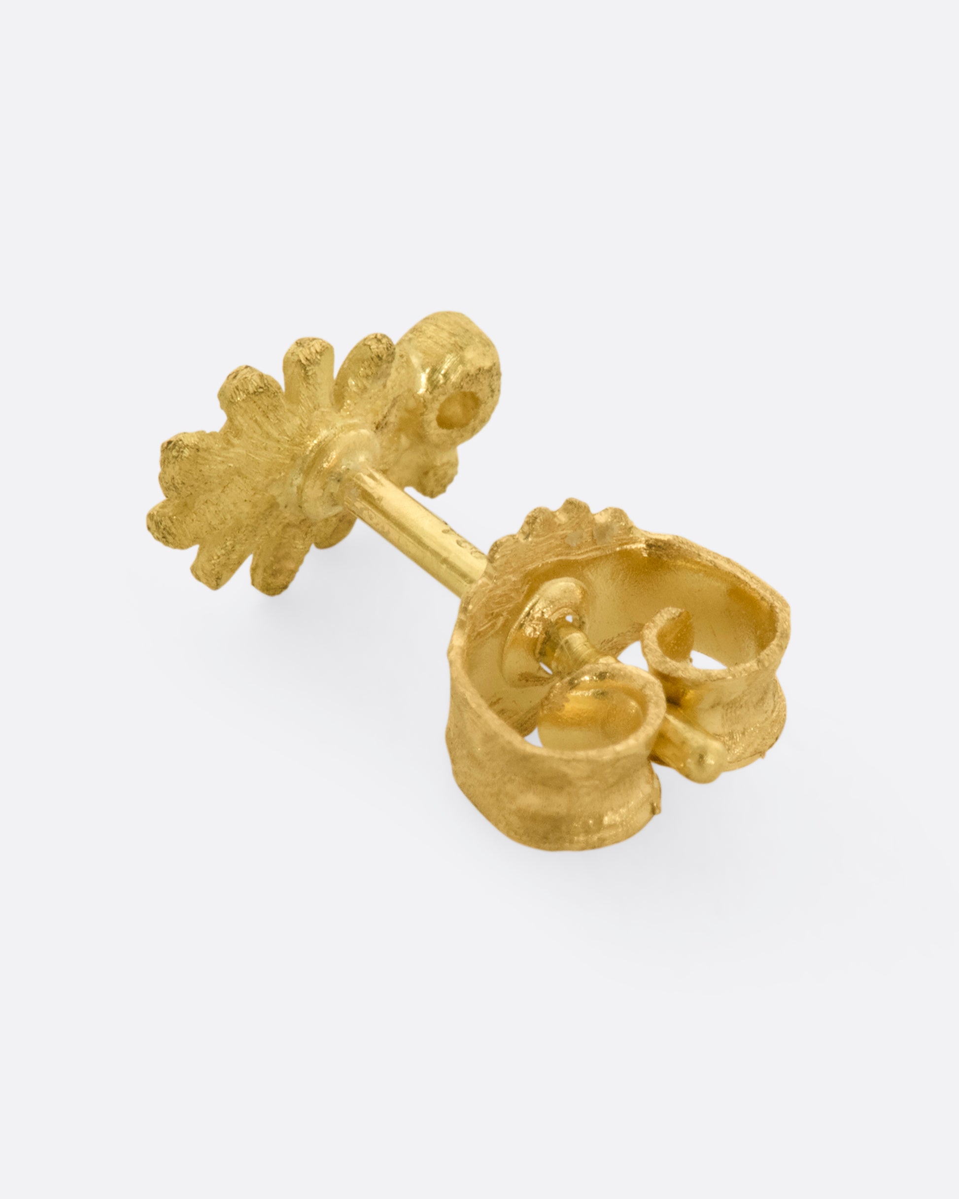 A yellow gold oak leaf earring with a diamond at the stem. View from the back including backing.