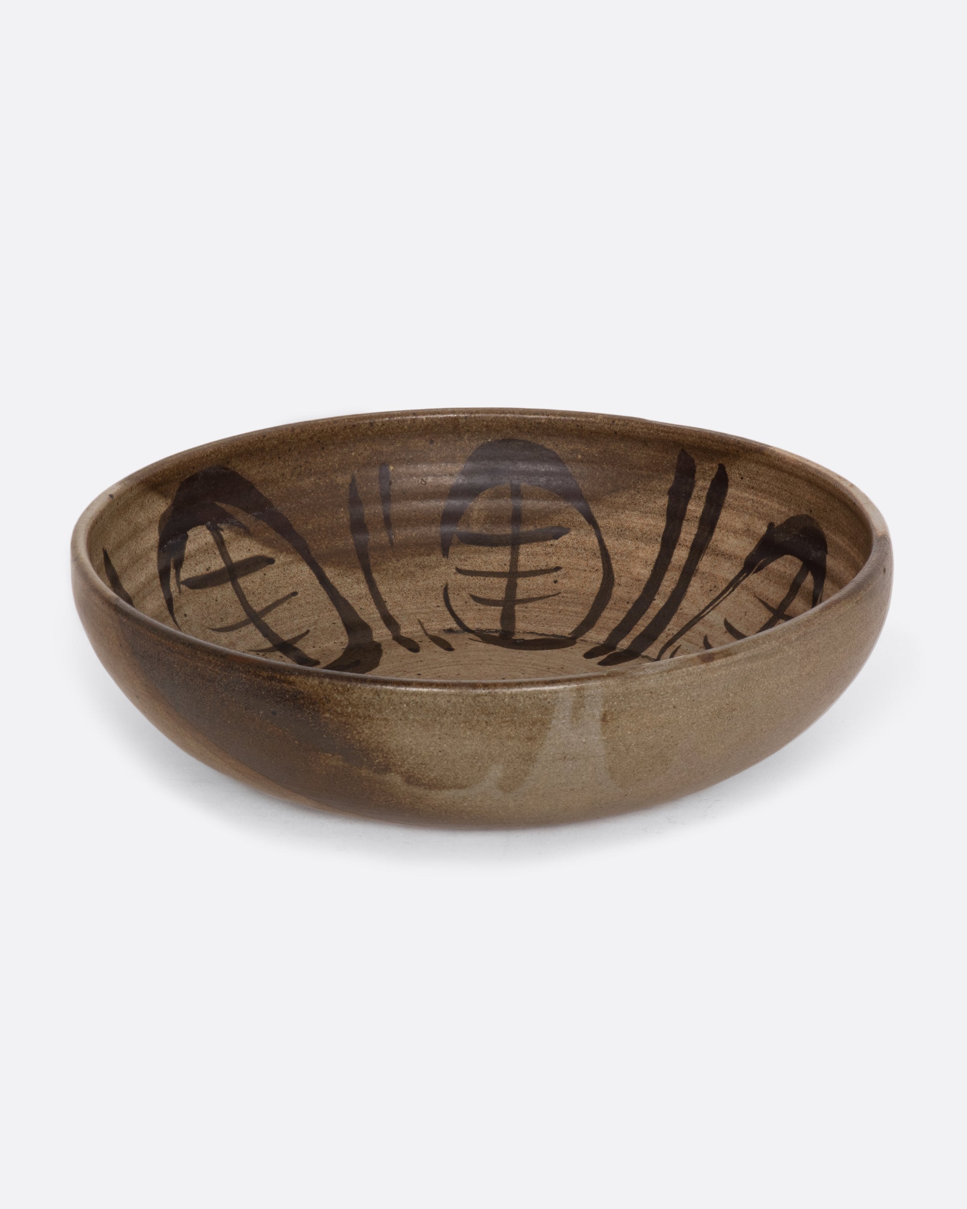 A ceramic deep bowl platter with painted abstract design on the interior. View sitting on a table.