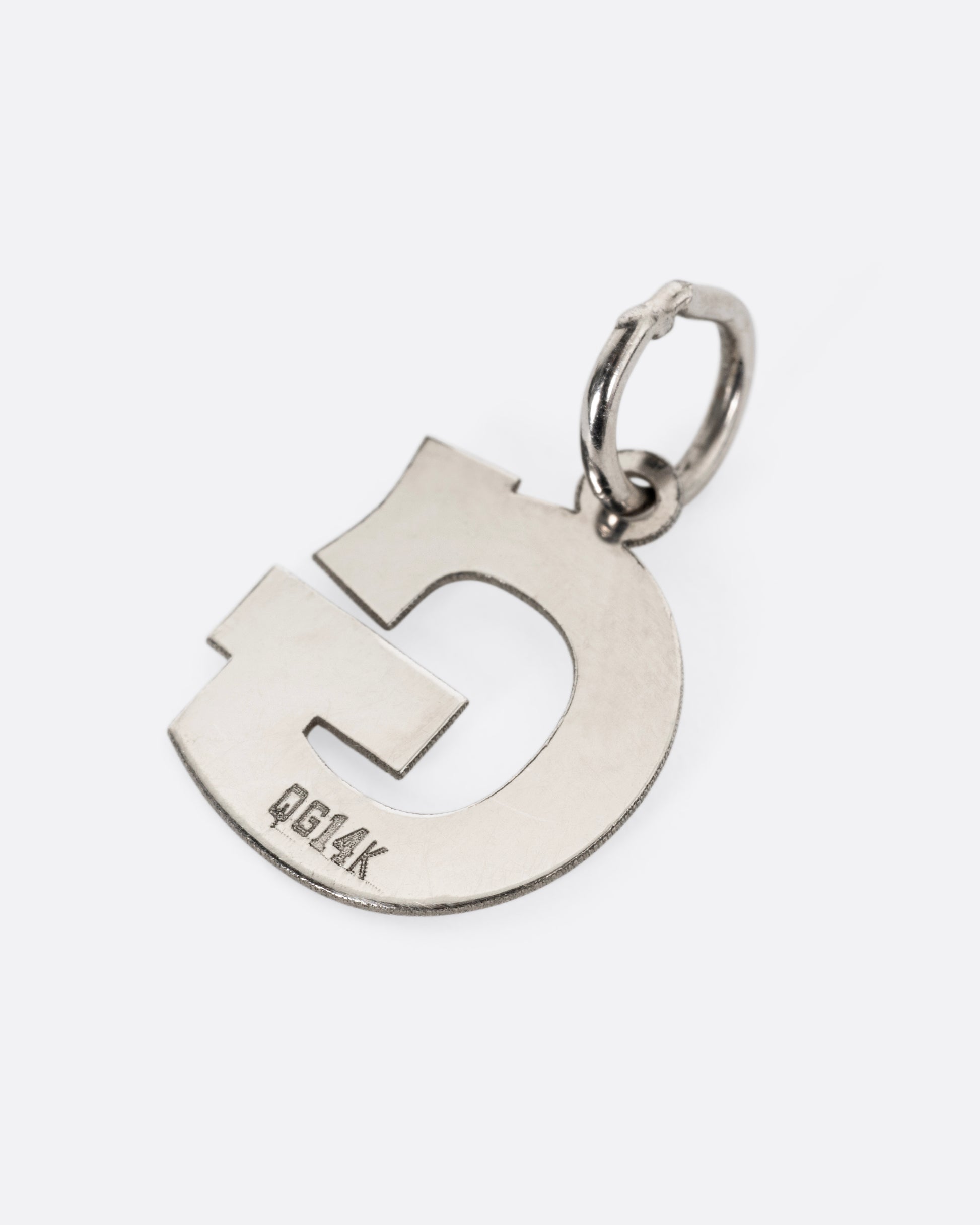 A white gold G pendant, shown from the back.
