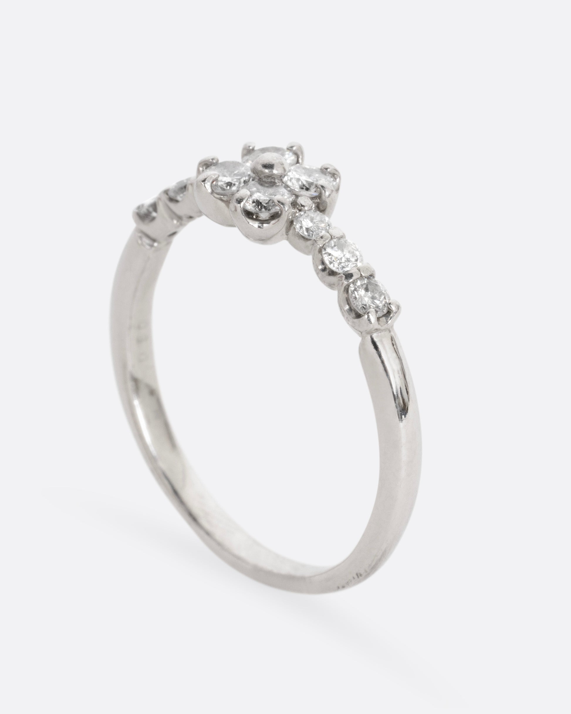 A platinum ring with an 'X' shape and diamonds, shown from the side standing up.