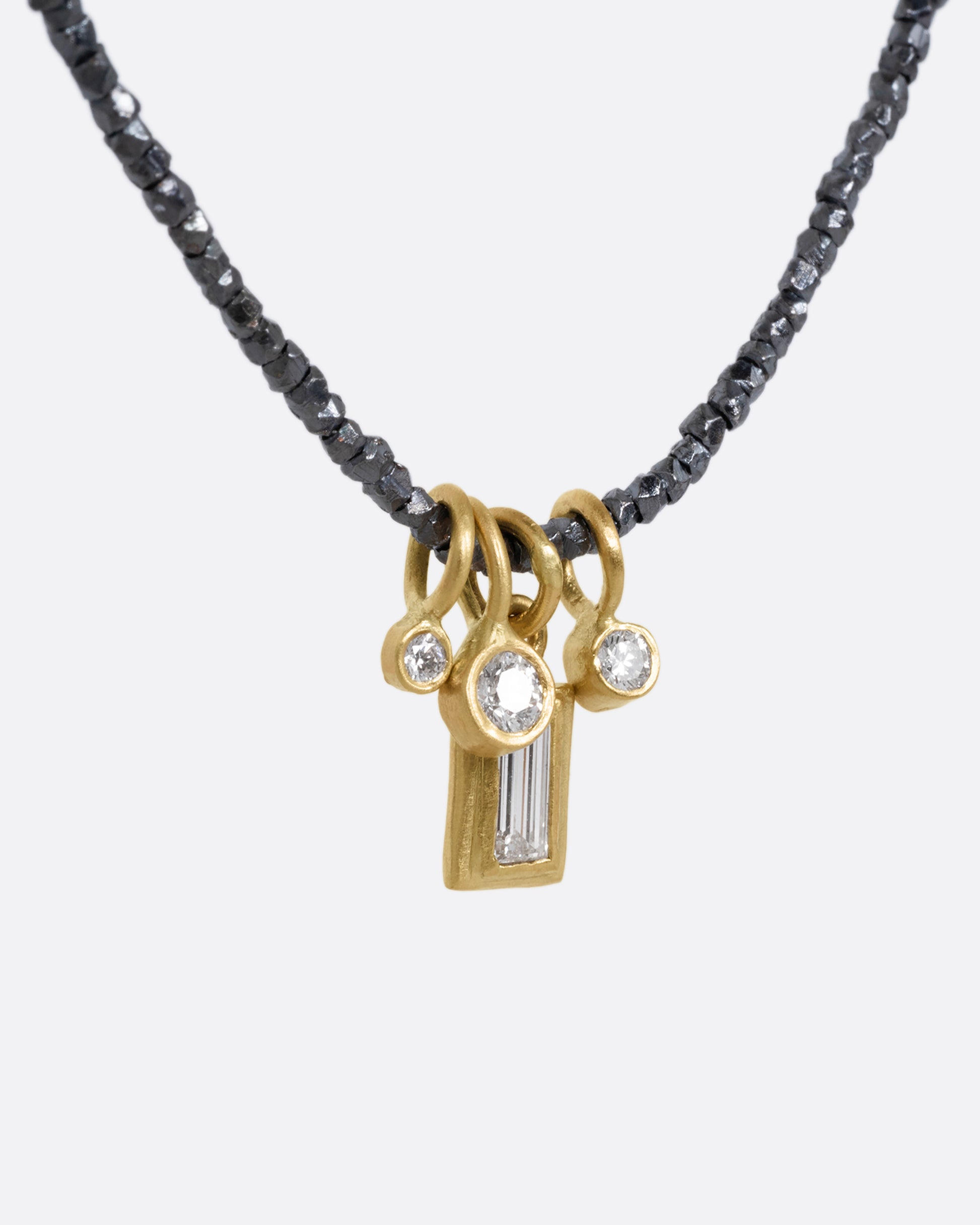 A necklace with oxidized silver Hill Tribe beads and a cluster of four brilliant white diamond charms. Shown from the side.