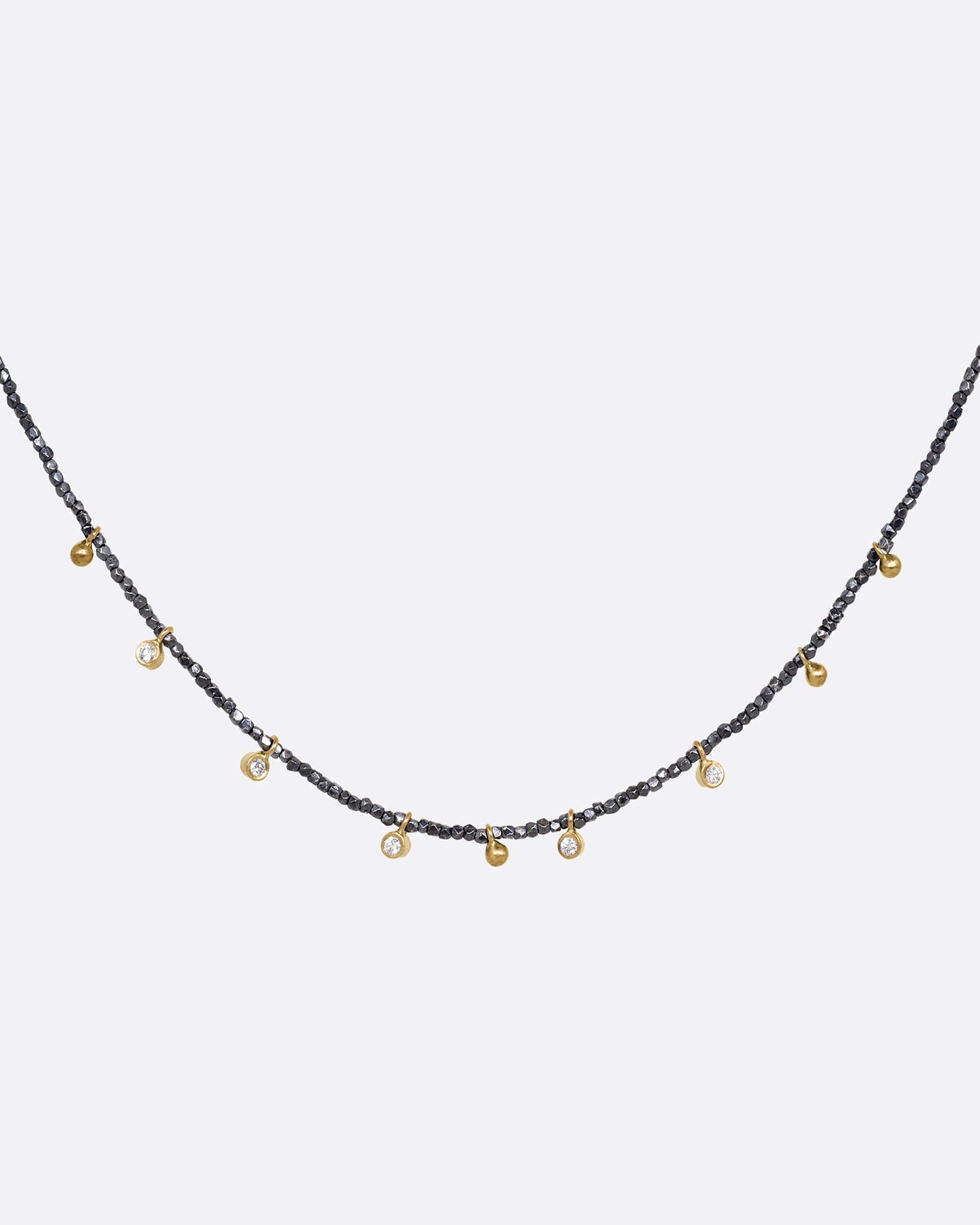 A necklace with five bezel set diamond charms and four gold drops interspersed among oxidized silver beads. Shown from the front.