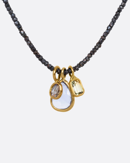 A necklace with oxidized silver Hill Tribe beads and a cluster of blue and green sapphires and a rose cut diamond. Shown from the front.