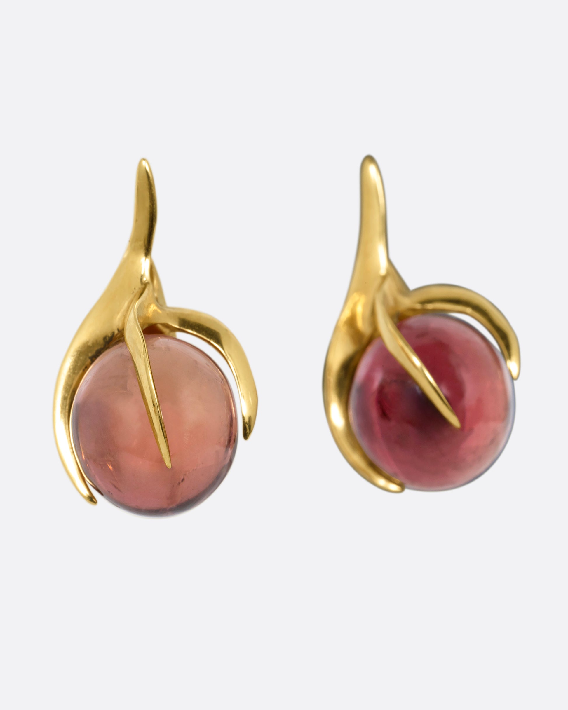 A pair of yellow gold stud earrings with claw settings cradling two tourmaline spheres. Shown from the side.