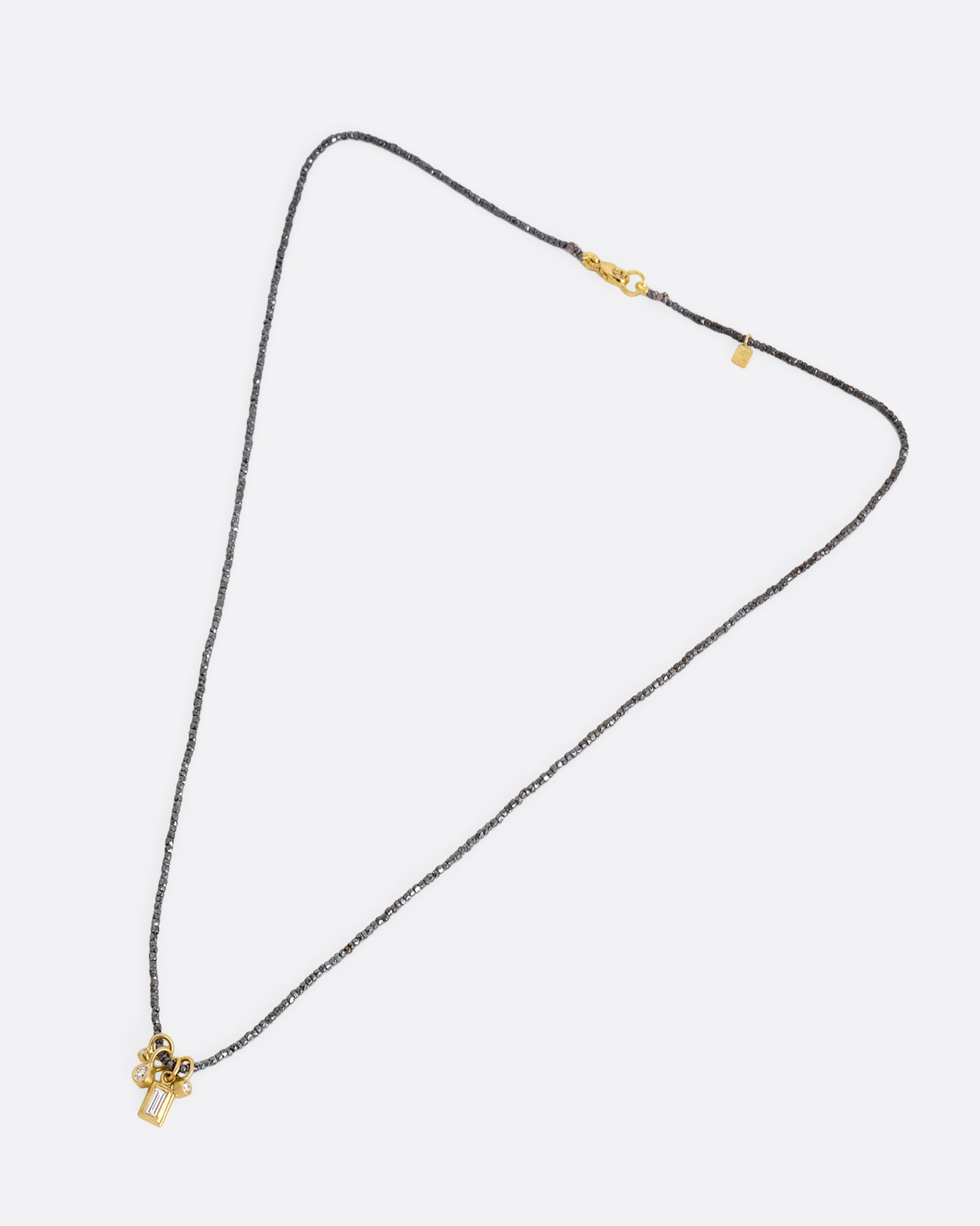 A necklace with oxidized silver Hill Tribe beads and a cluster of four brilliant white diamond charms. Shown lying flat from the front.