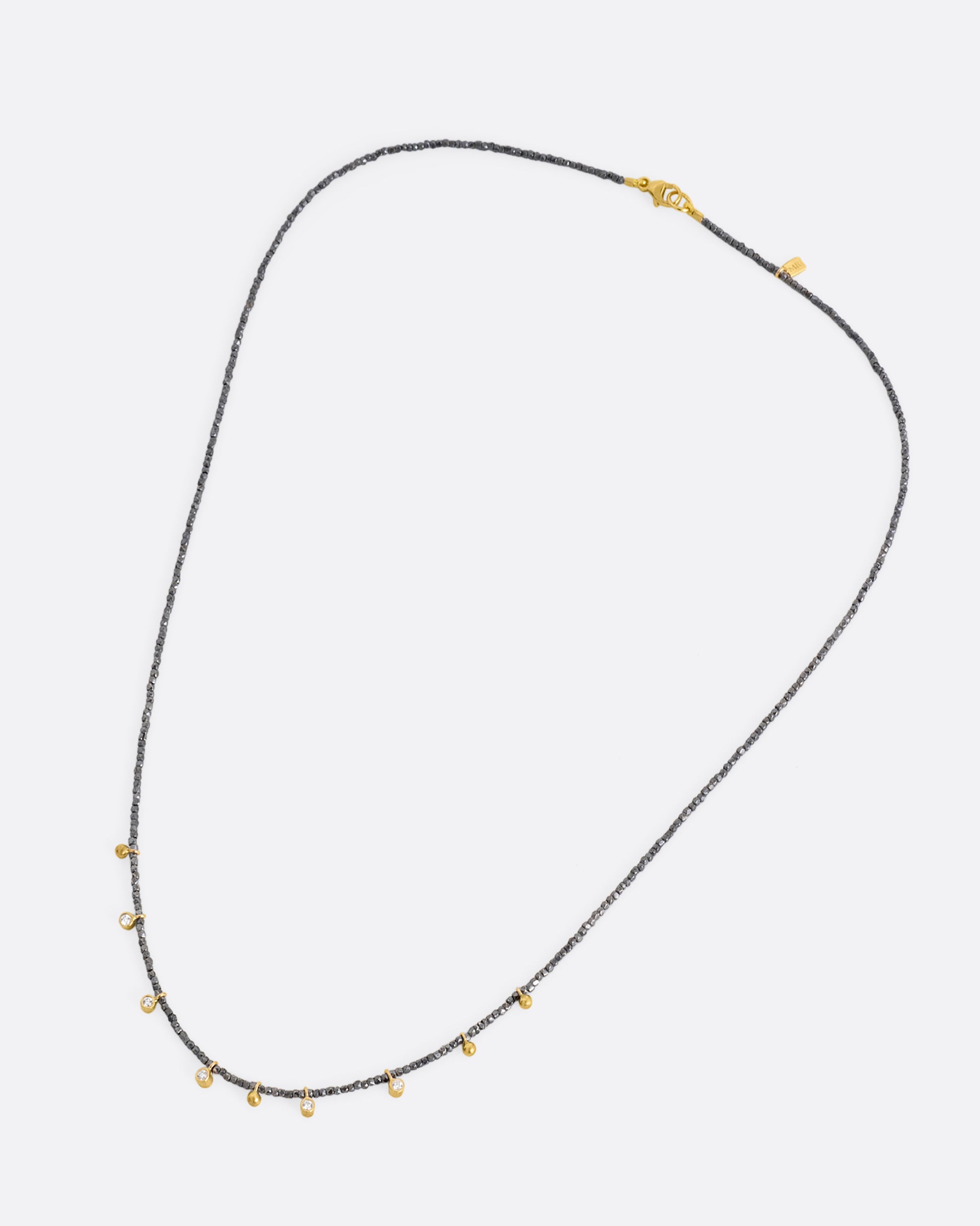 A necklace with five bezel set diamond charms and four gold drops interspersed among oxidized silver beads. Shown from the front.