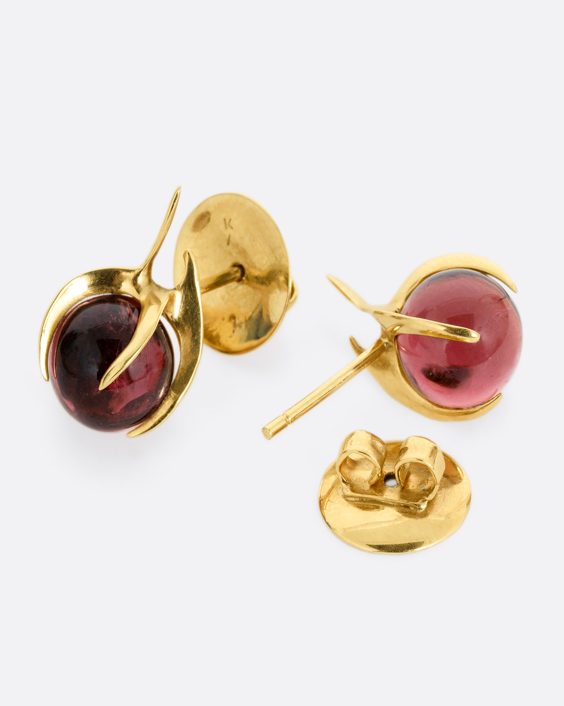 A pair of yellow gold stud earrings with claw settings cradling two tourmaline spheres. One earring is shown from the front, the other is shown from the back open.