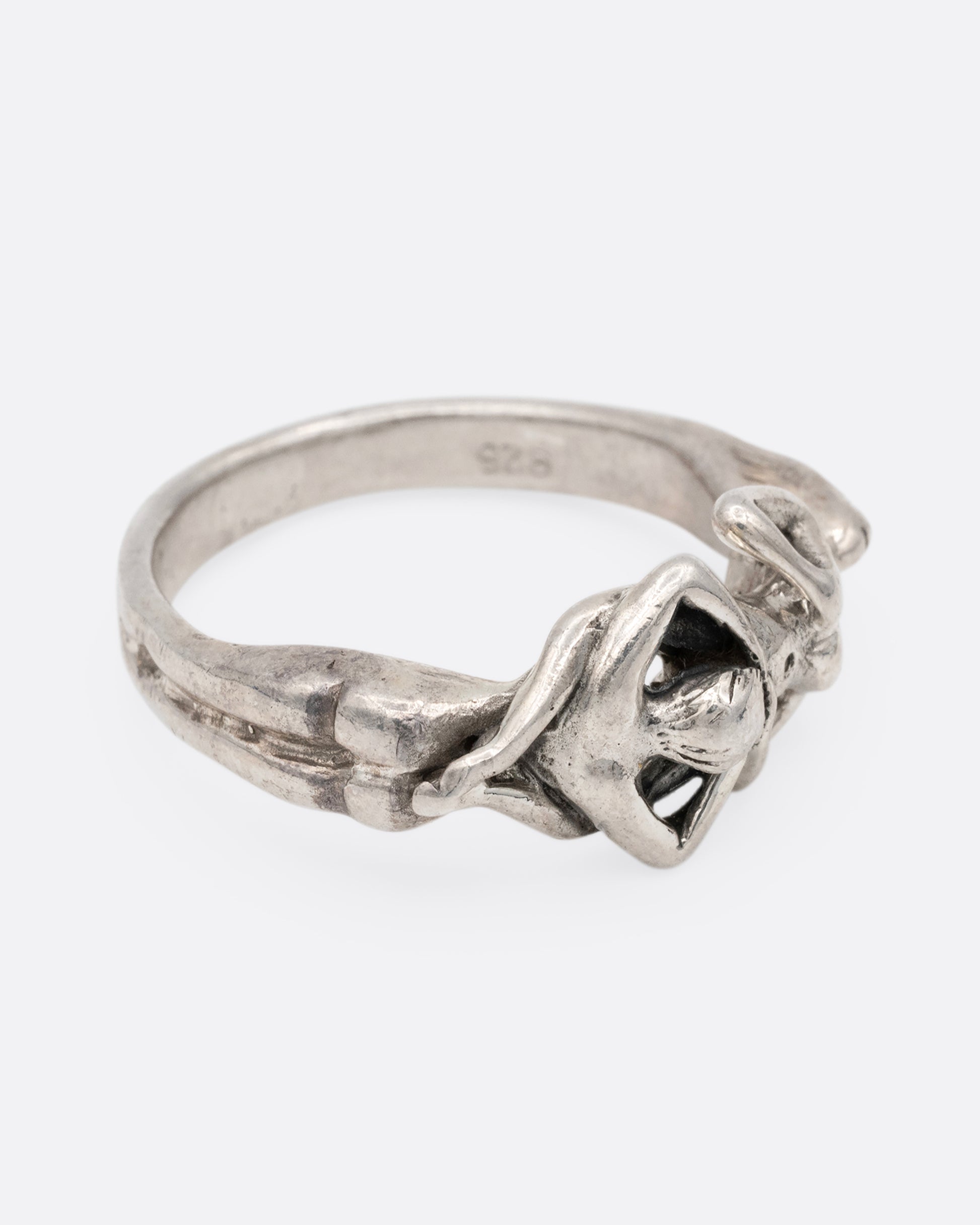 A silver ring with an erotic couple. Shown from the side.