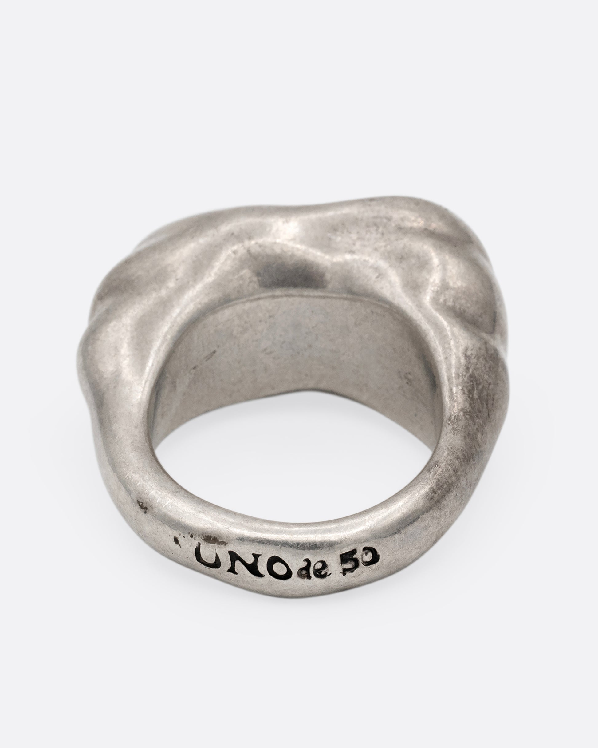 A silver ring with a cluster of free moving hoops nestled into its towering face. Shown from the back.