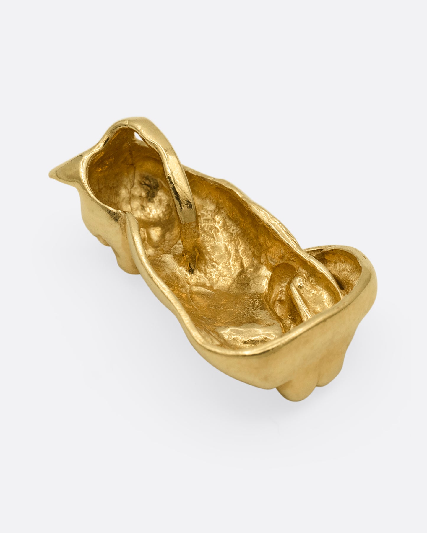 A yellow gold cat charm, shown from the back. 