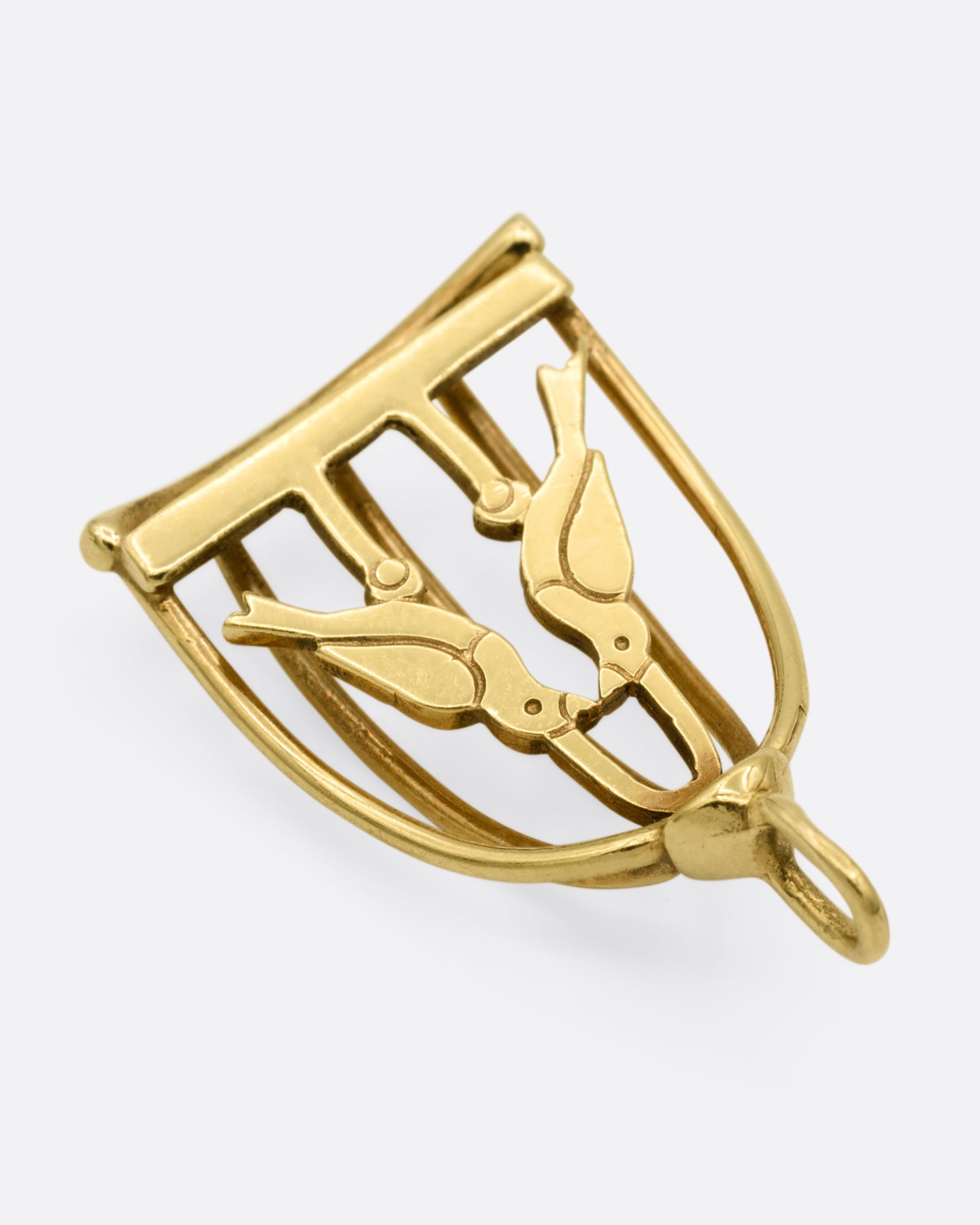 A yellow gold birdcage charm with two lovebirds in it. Shown from the back.