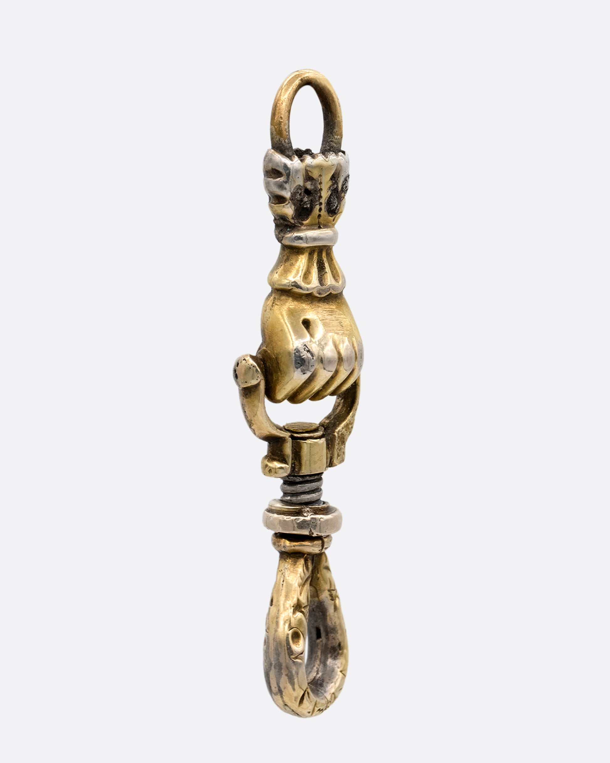 A yellow gold charm holder with a 'knocker' style hand in a fist between each looped end. shown from the side.