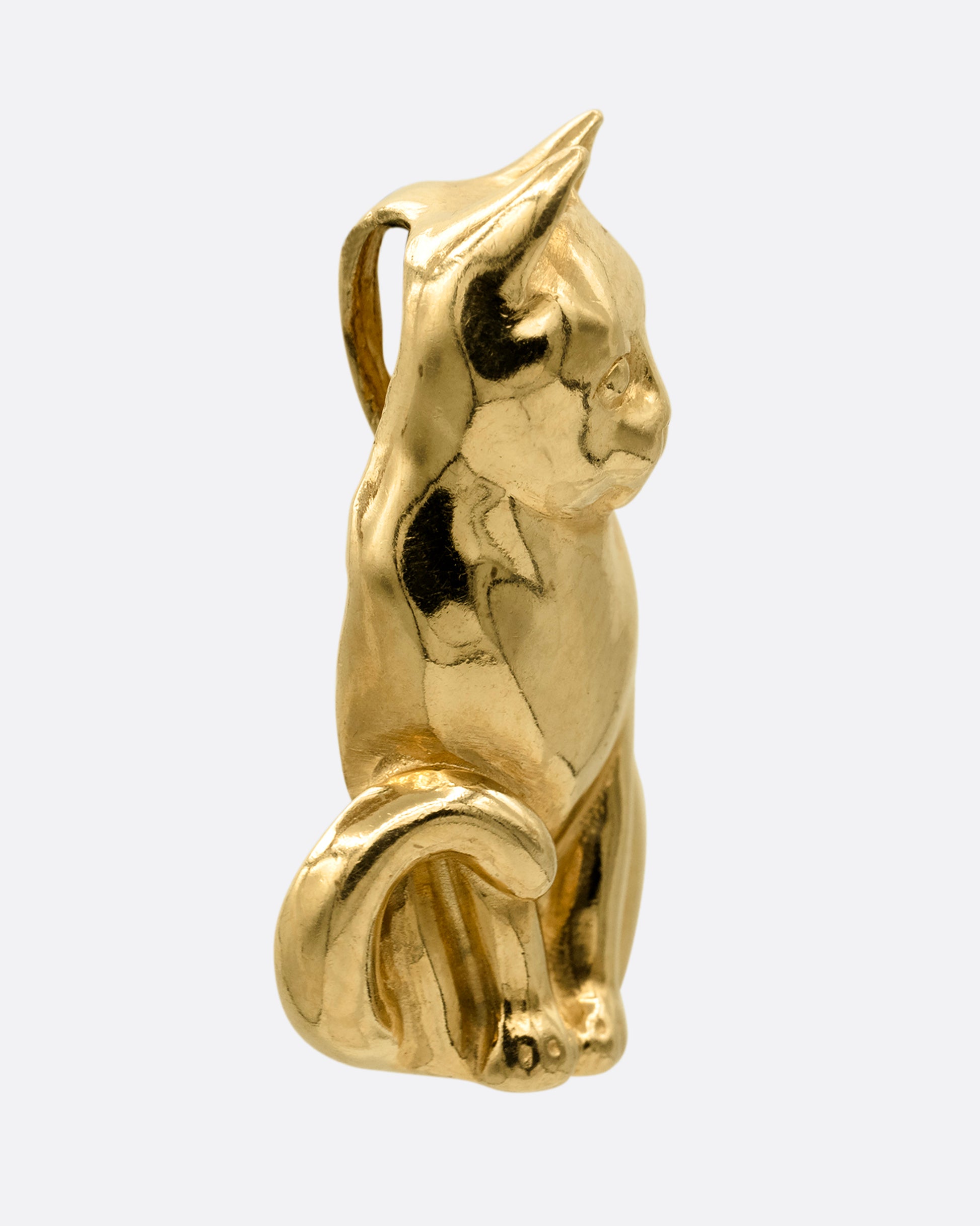 A yellow gold cat charm, shown from the side. 