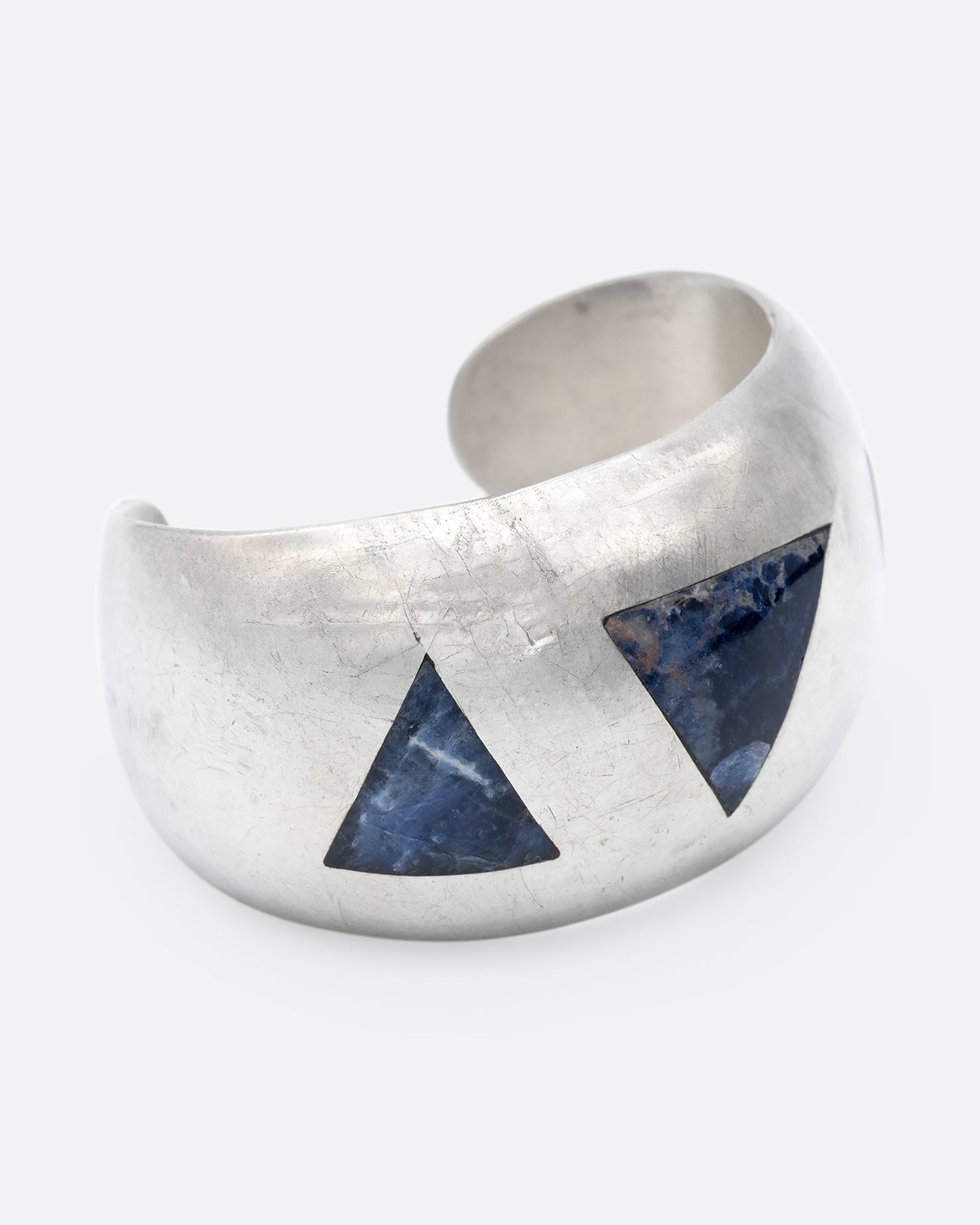 A broad silver cuff with three large lapis triangles along its convex front. Shown from the side.
