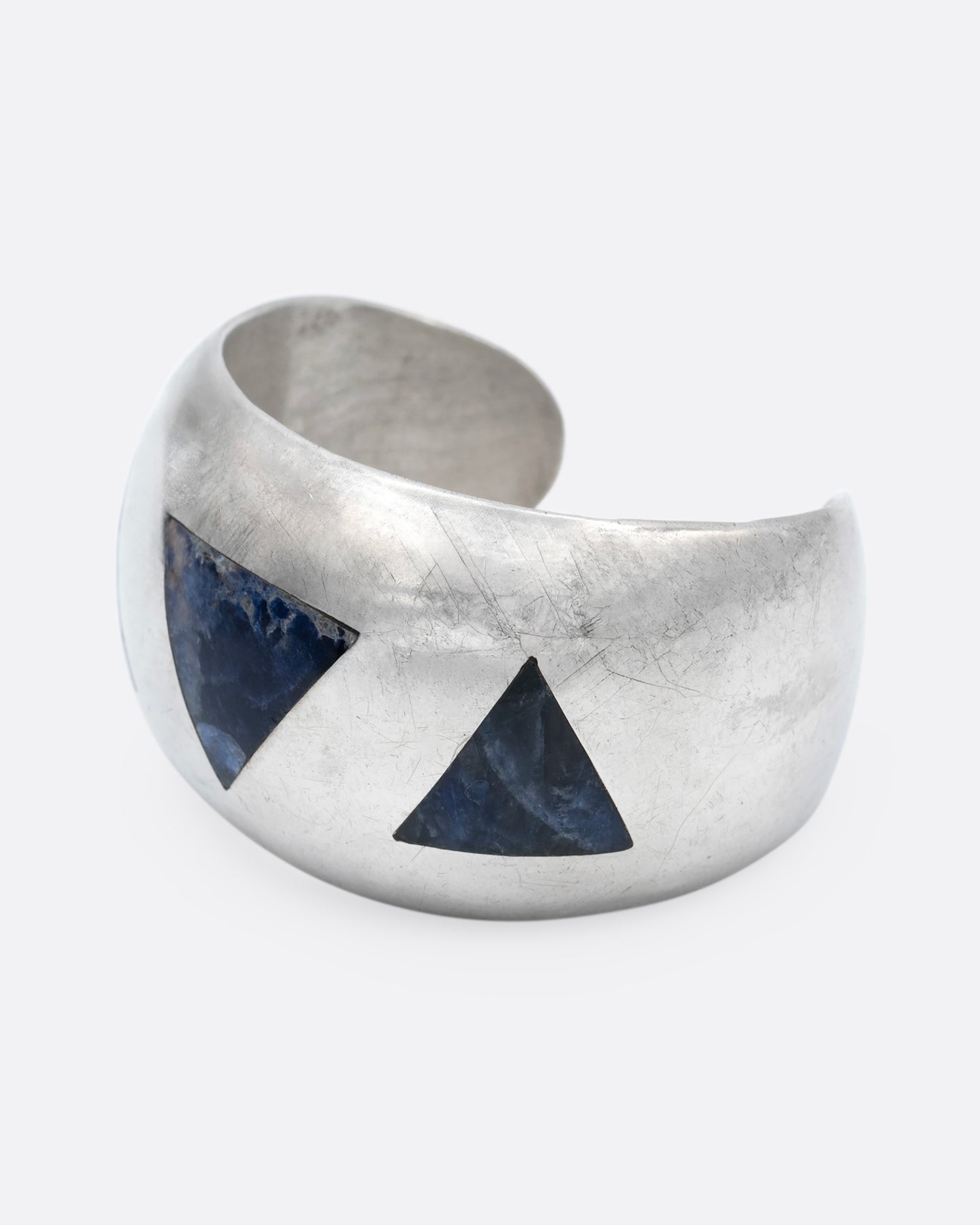 A broad silver cuff with three large lapis triangles along its convex front. Shown from the side.
