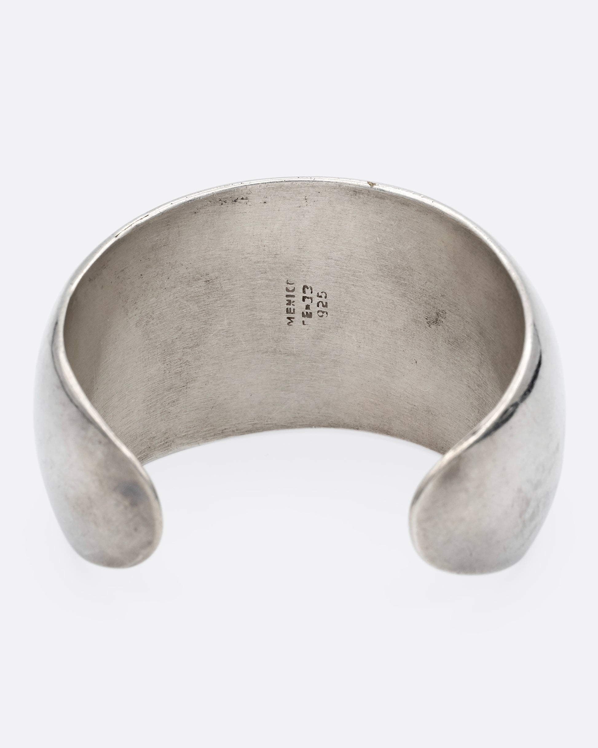 A broad silver cuff with three large lapis triangles along its convex front. Shown from the back.
